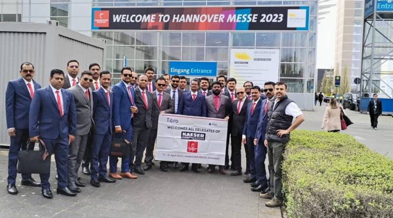 A group of professionals posing with a banner at Hannover Messe 2023.
