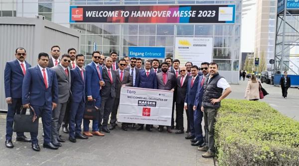 A group of professionals posing with a banner at Hannover Messe 2023.
