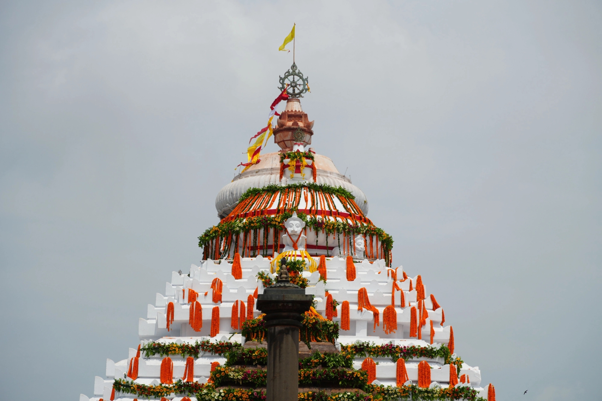 A beautifully decorated Indian temple dome with vibrant flowers and flags under a clear sky