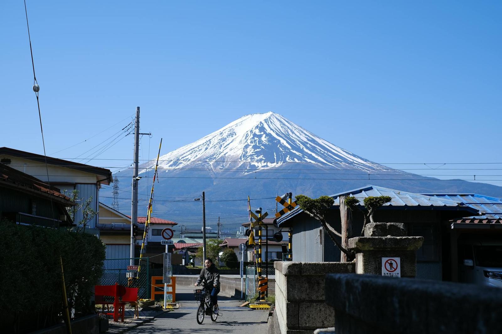 A cyclist riding through a small town with Mount Fuji rising behind