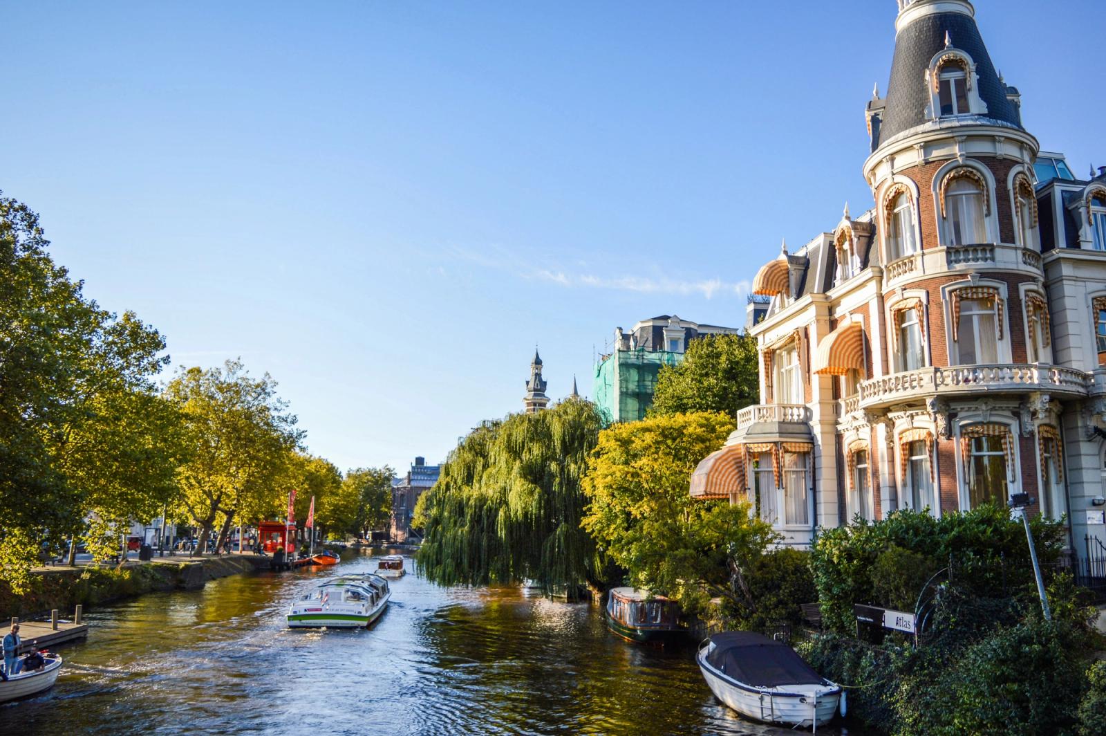 Picturesque view of Amsterdam canal with historical architecture and boats on a sunny day