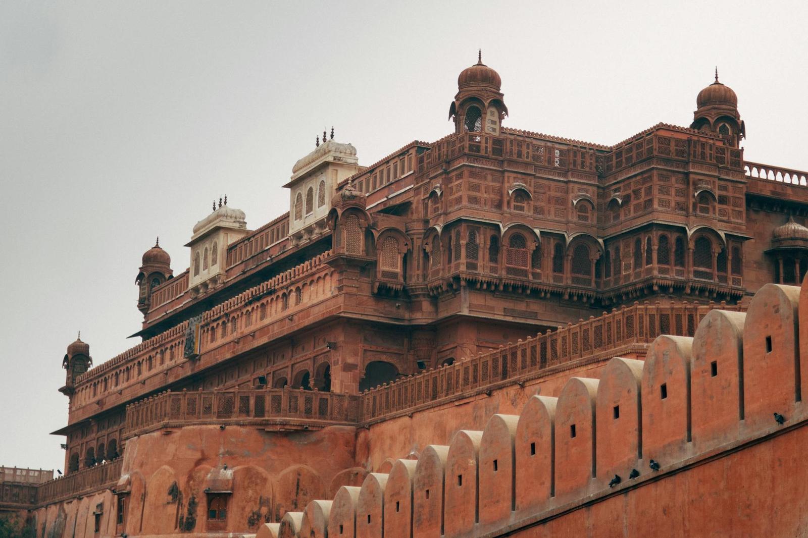 A red sandstone fort facade with domed pavilions along its ramparts
