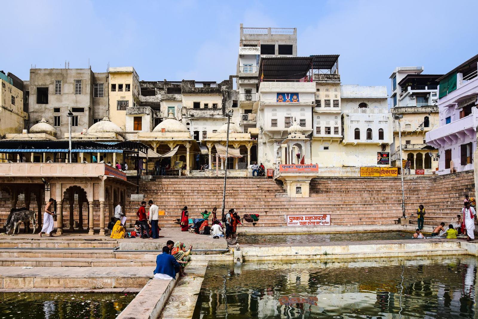 Bathing ghat with historic buildings and a morning crowd along stepped riverside