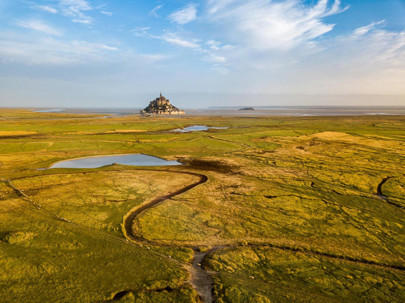 Aerial view of a tidal island abbey surrounded by green marshland