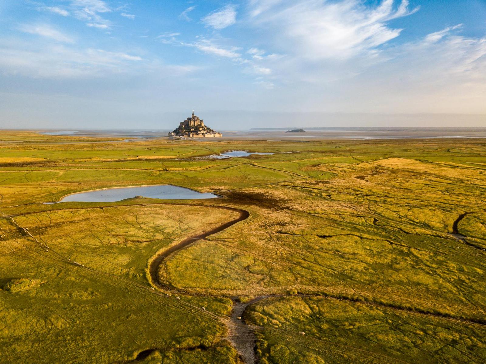Aerial view of a tidal island abbey surrounded by green marshland