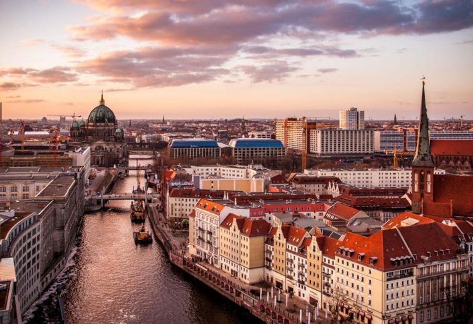 The illuminated skyline and river of a German city at dusk