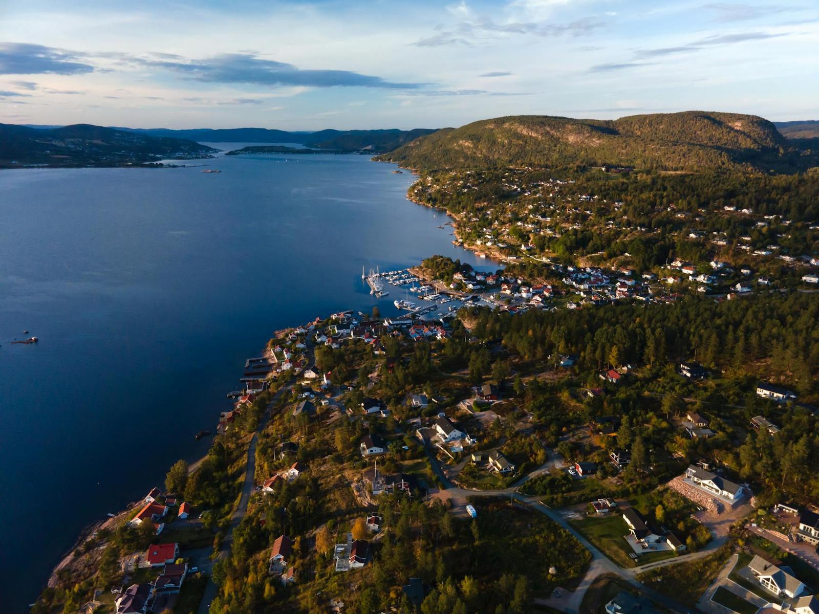 Aerial view of a coastal town scattered along a forested fjord at dusk