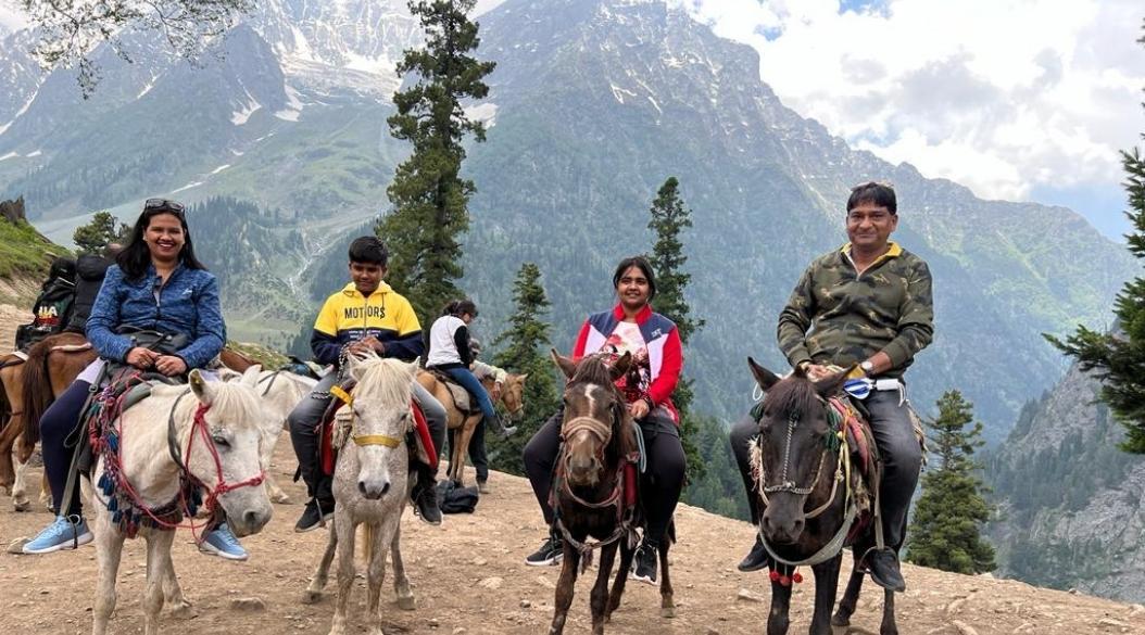 Four people sitting on horses along a rocky trail