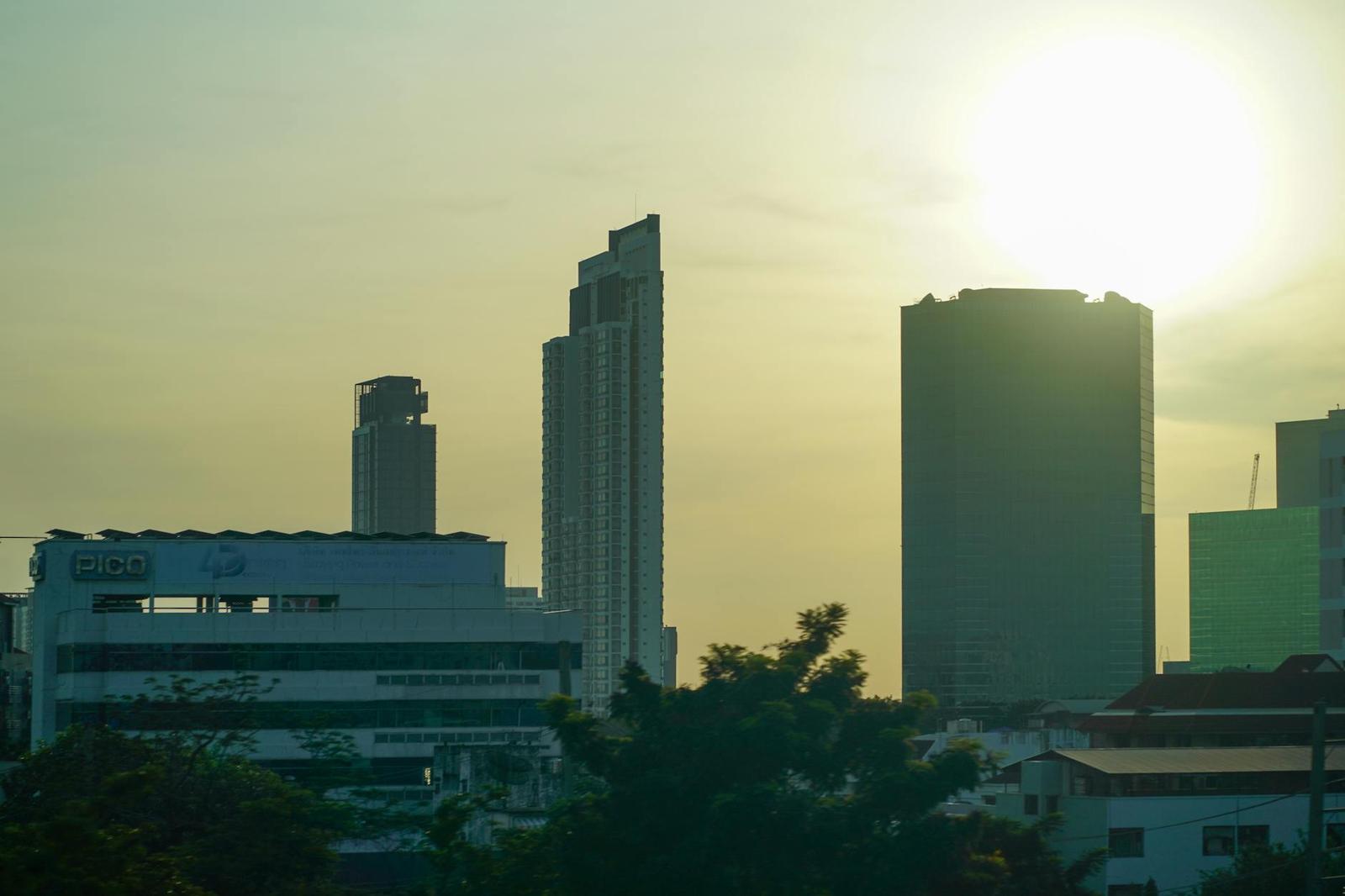 Silhouetted skyscrapers backlit by a hazy setting sun