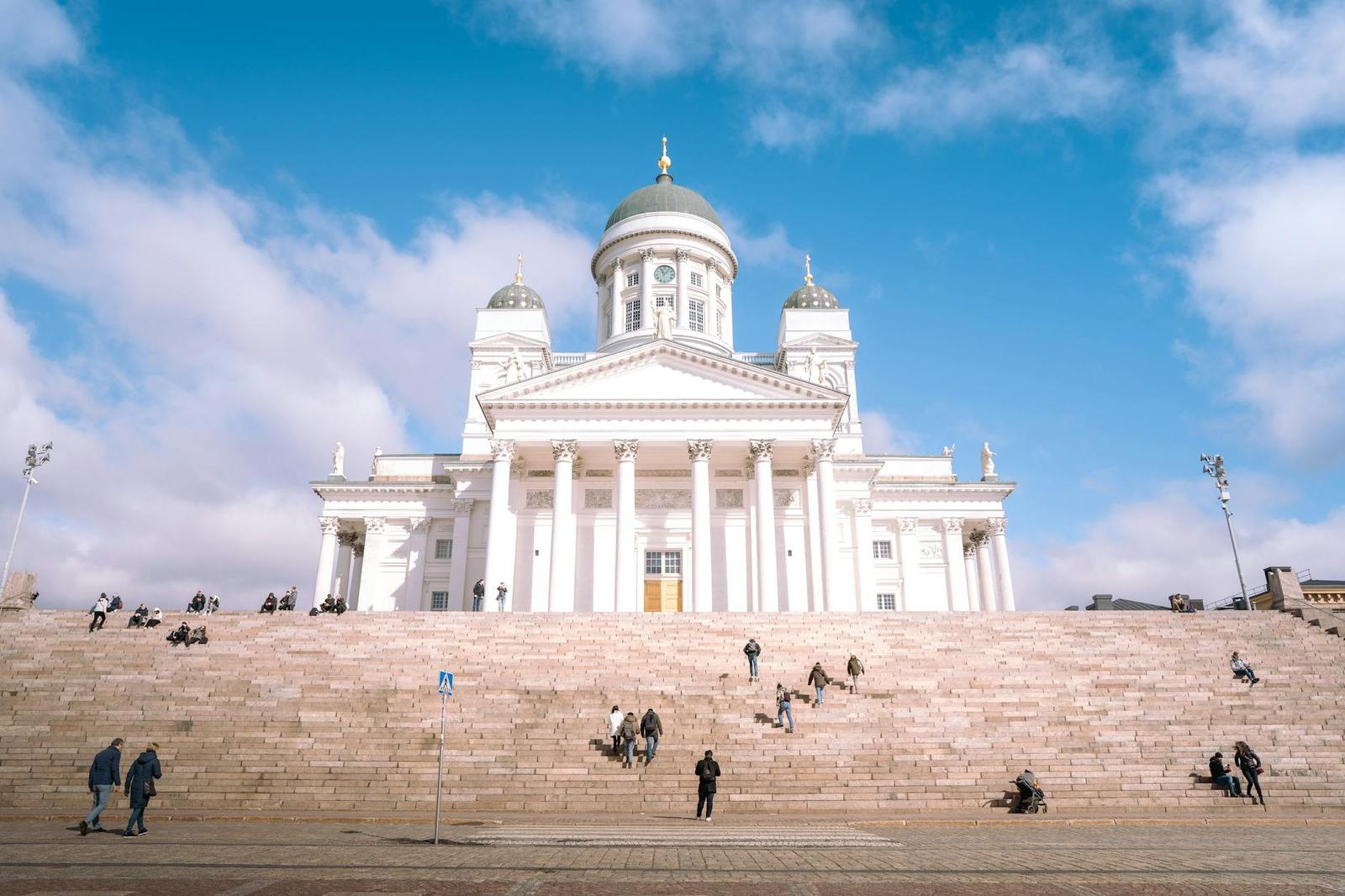 A wide-angle shot of Helsinki Cathedral featuring steps and people on a sunny day