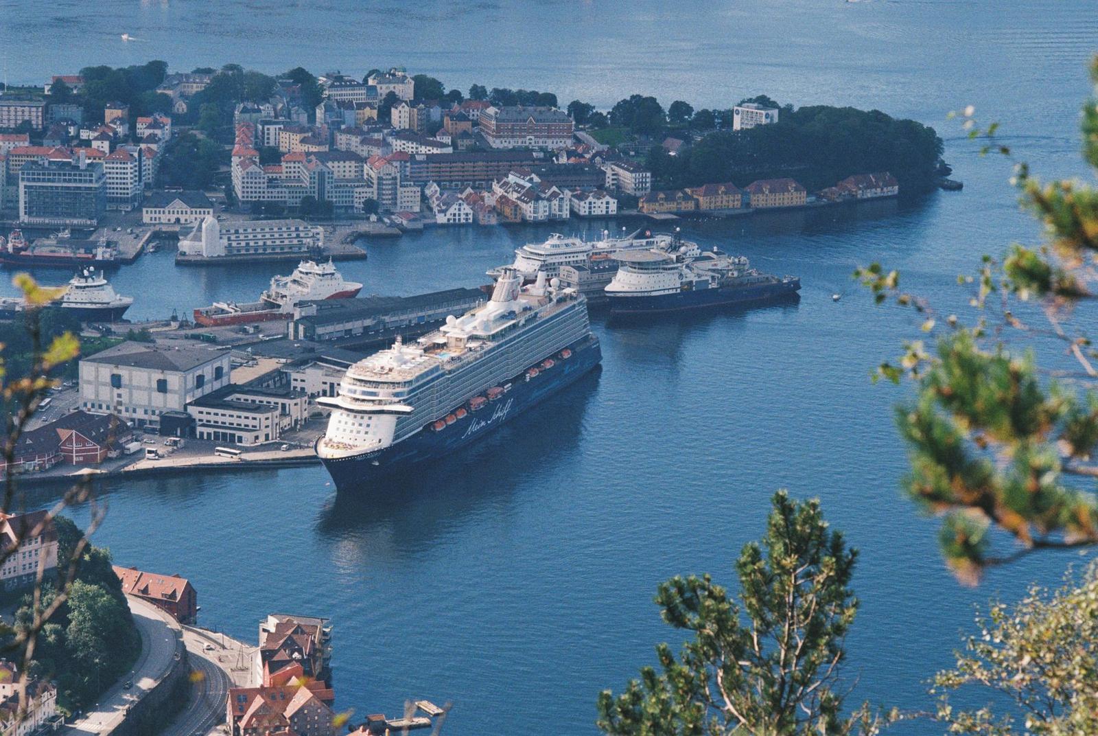An aerial view of cruise ships docked in a harbour surrounded by a coastal town