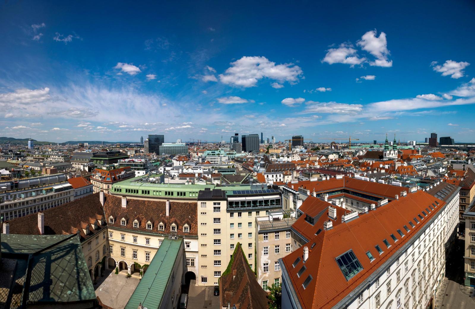 Wide-angle view of Vienna skyline featuring mix of historical and modern architecture under a bright blue sky