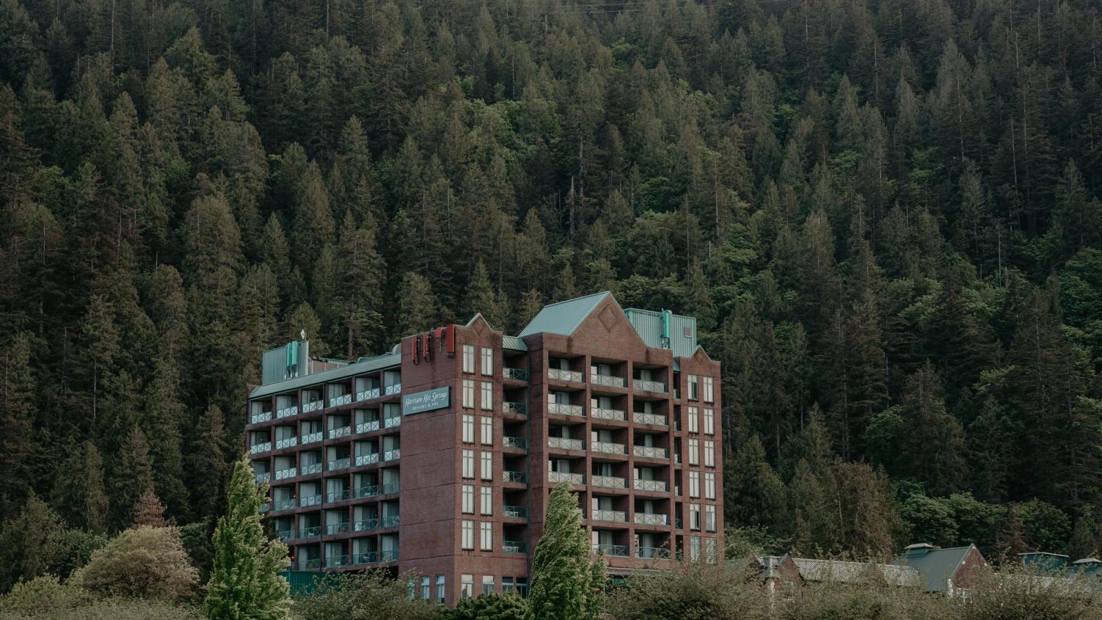 A modern resort building surrounded by dense forest and green hills, offering a tranquil escape