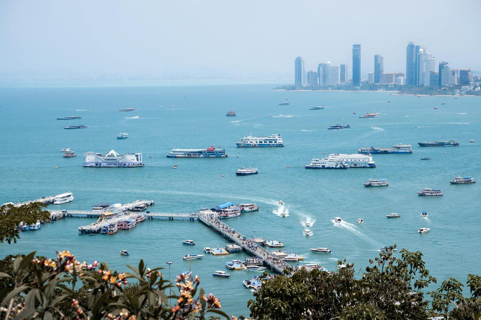 Aerial view of tour boats clustered off a hazy coastal city skyline