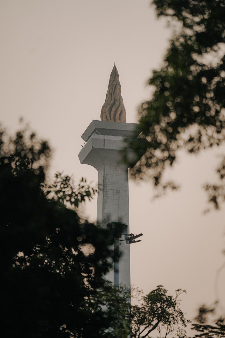 A view of Monumen Nasional framed by trees during sunset in Jakarta, Indonesia