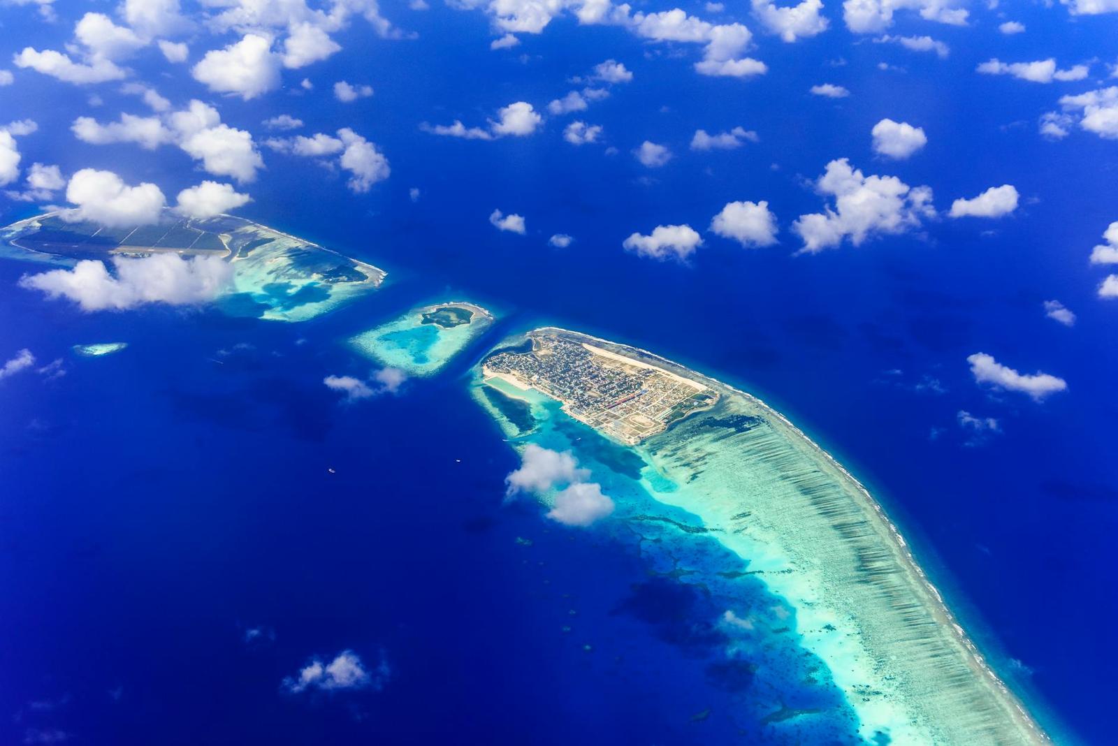 Aerial view of scattered reef islands under a cloud-dappled sky