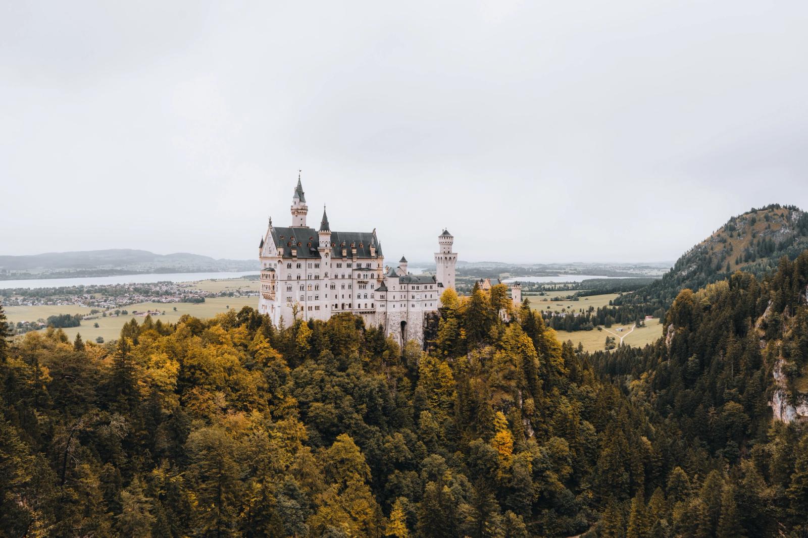 Neuschwanstein Castle perched on a forested hilltop in autumn