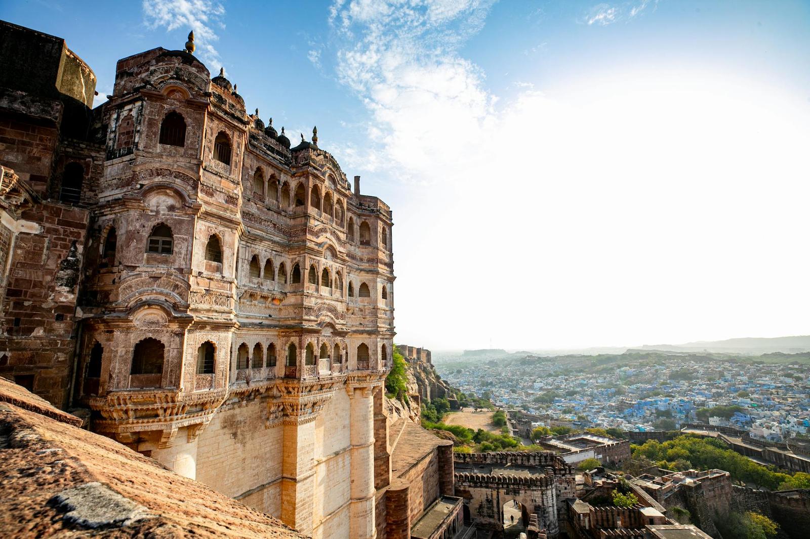 Sandstone fort tower overlooking a hillside town of blue-painted houses