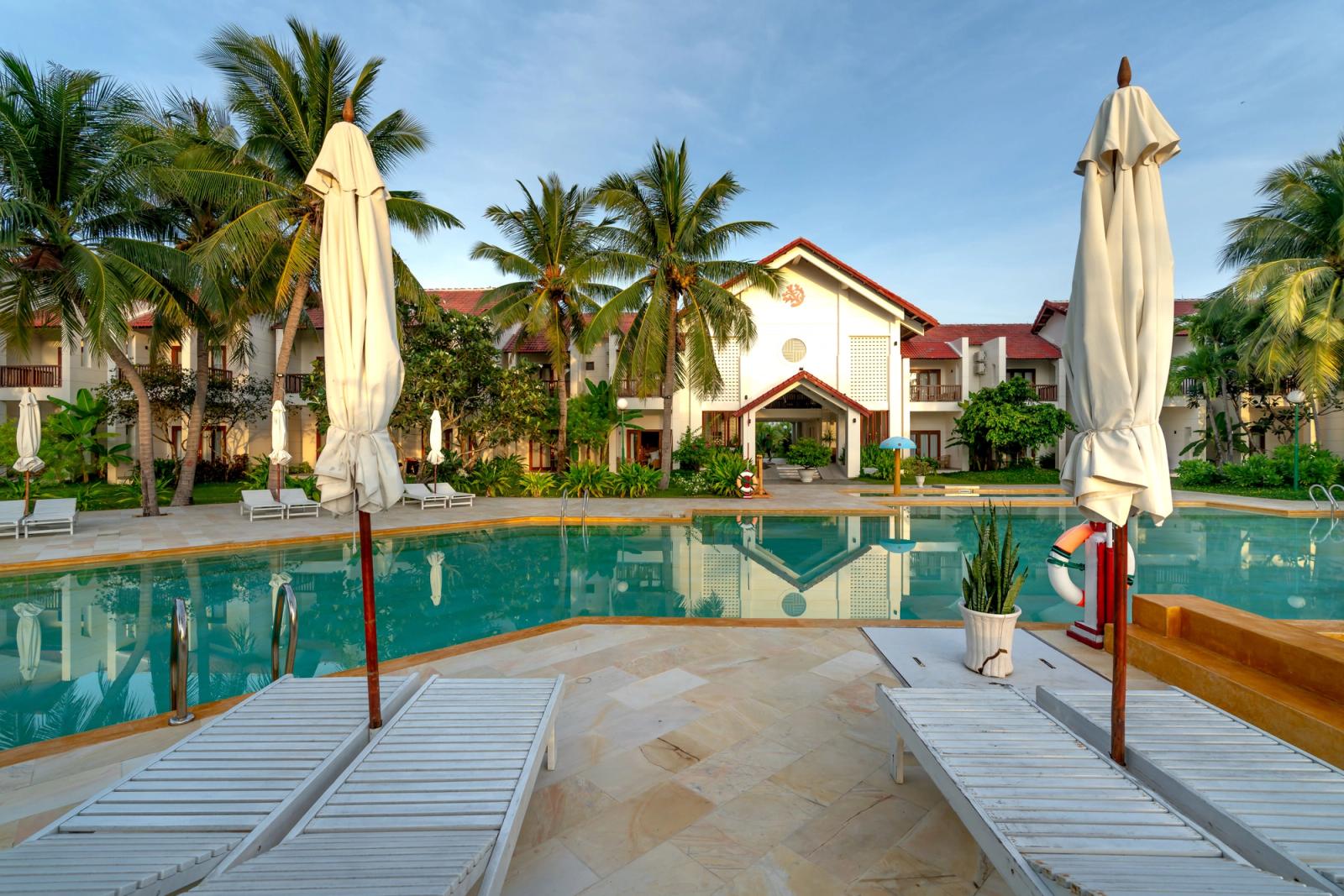 Tranquil luxury resort showcasing a serene pool, palm trees, and elegant architecture for a relaxing vacation