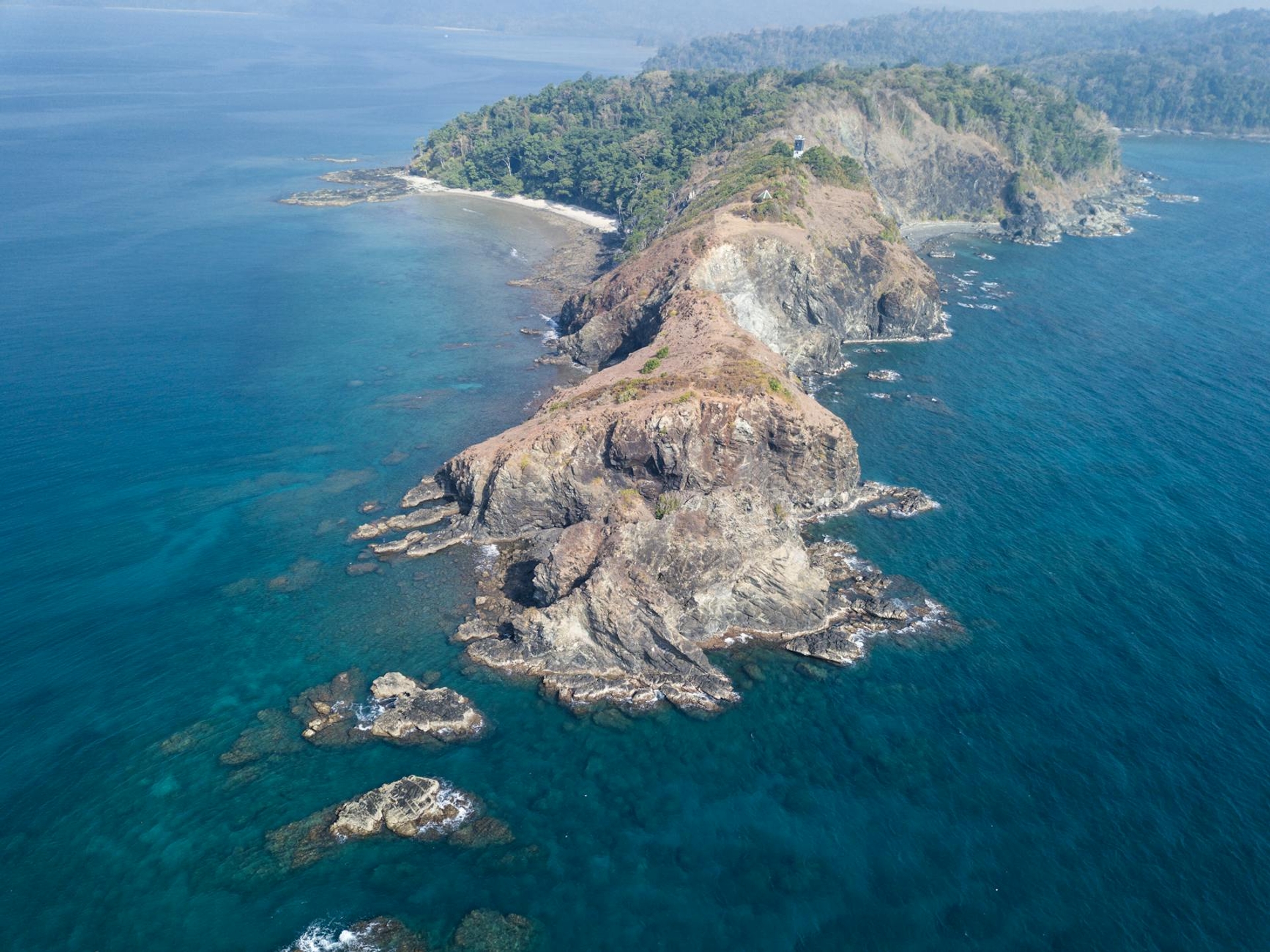 Aerial view of a rugged coastal headland jutting into blue ocean