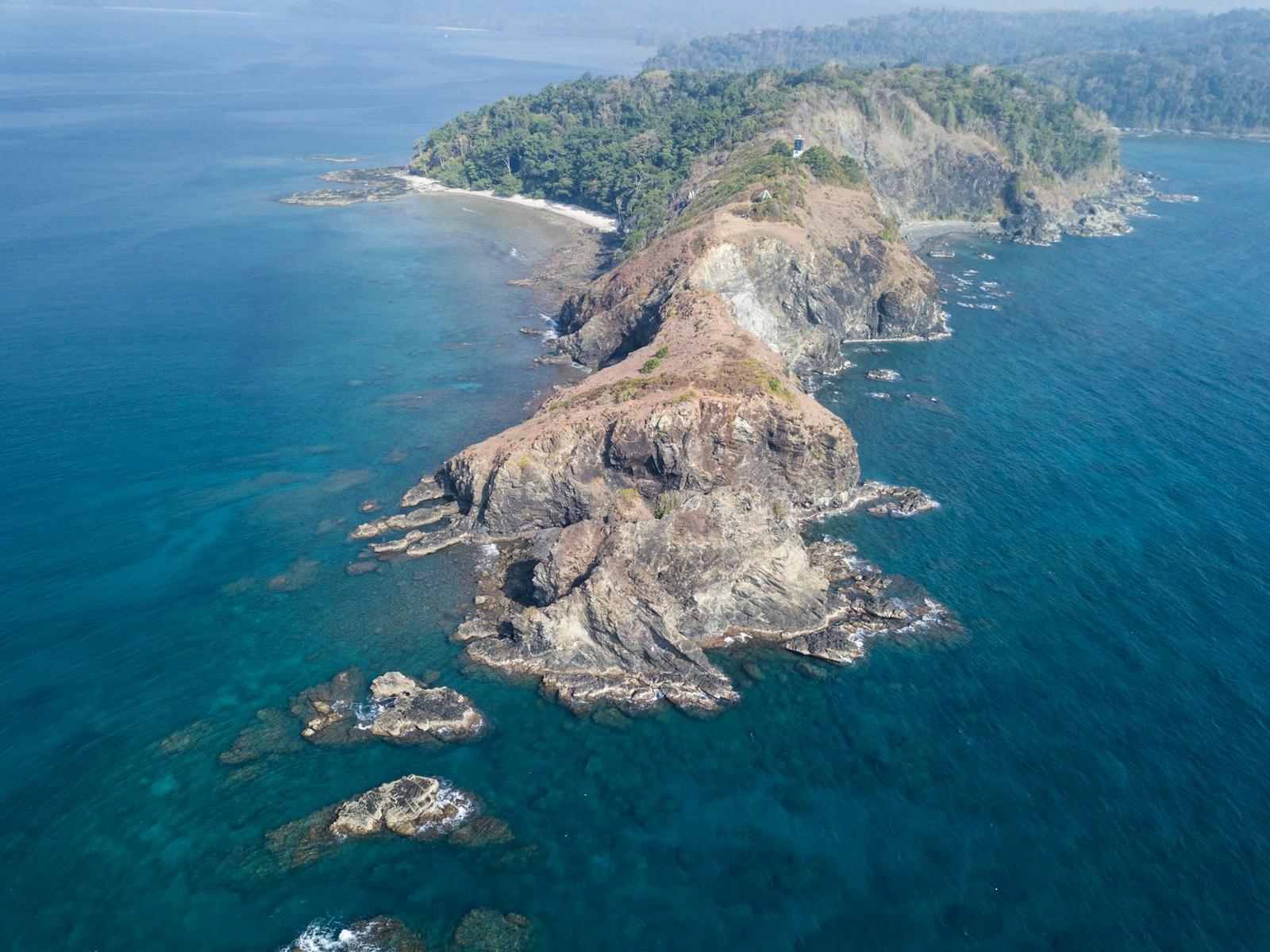 Aerial view of a rugged coastal headland jutting into blue ocean