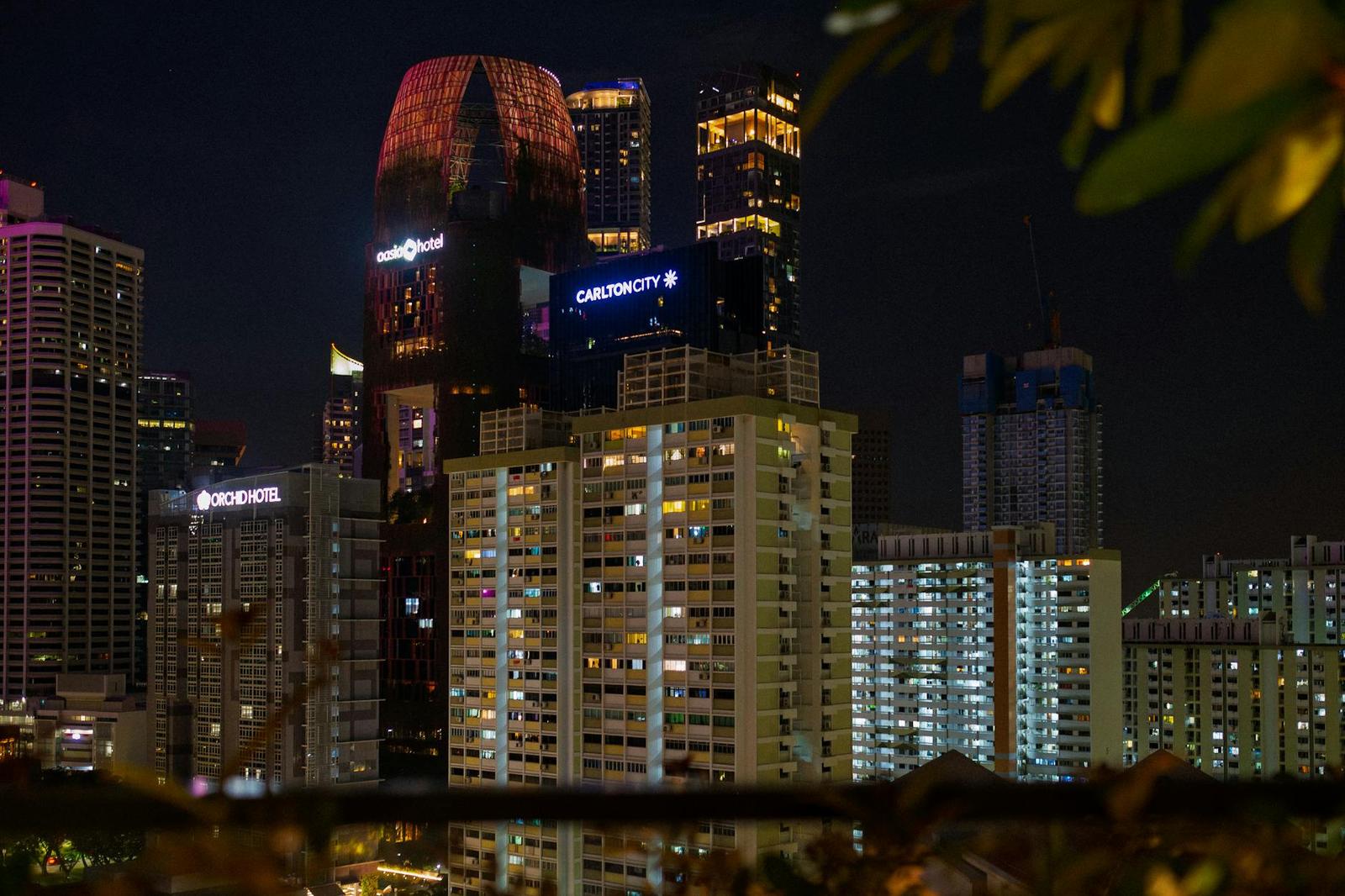 Illuminated skyscrapers rising above lit apartment towers on a hazy night