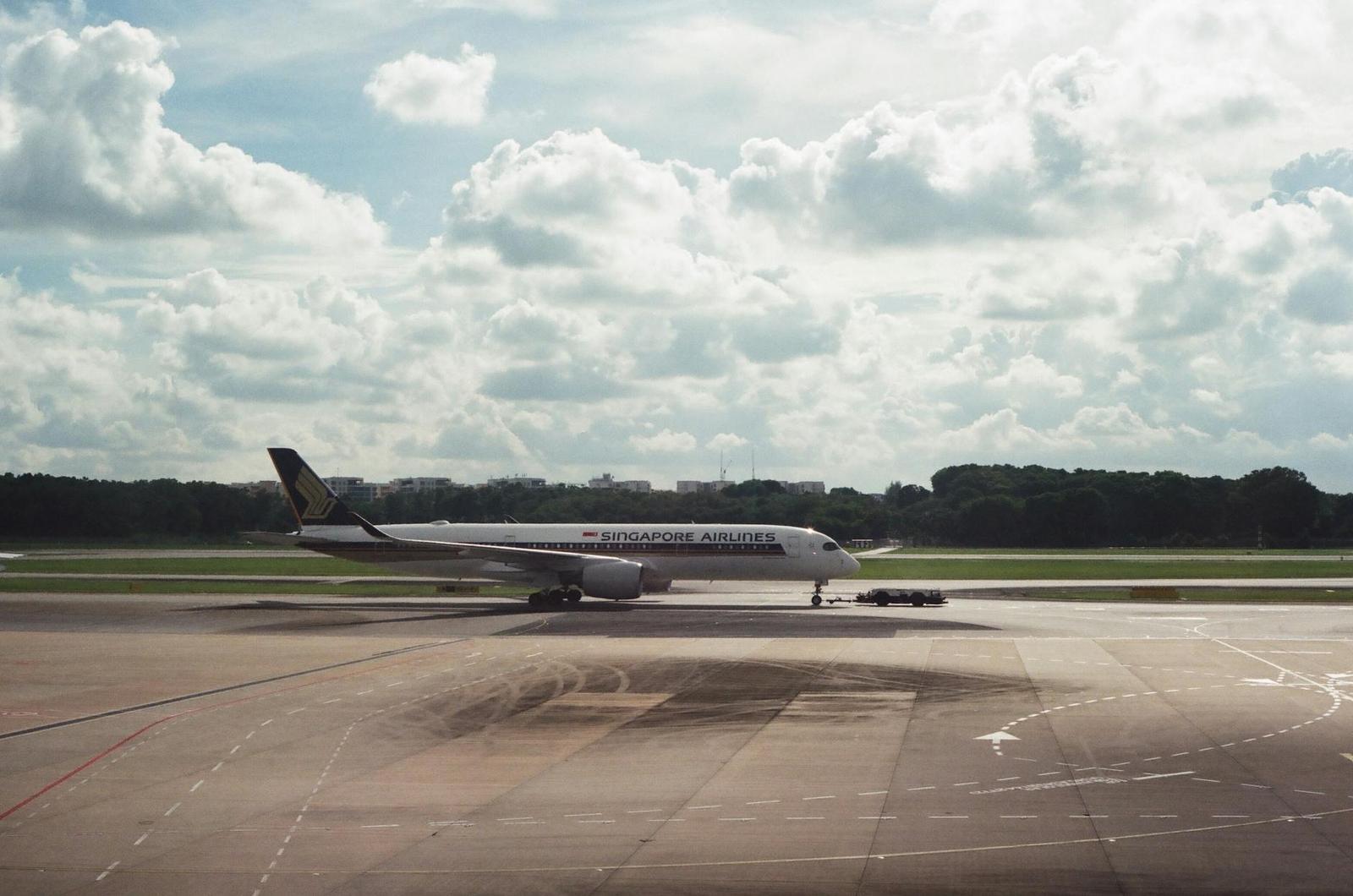 A Singapore Airlines aircraft taxiing on a runway under a cloudy sky
