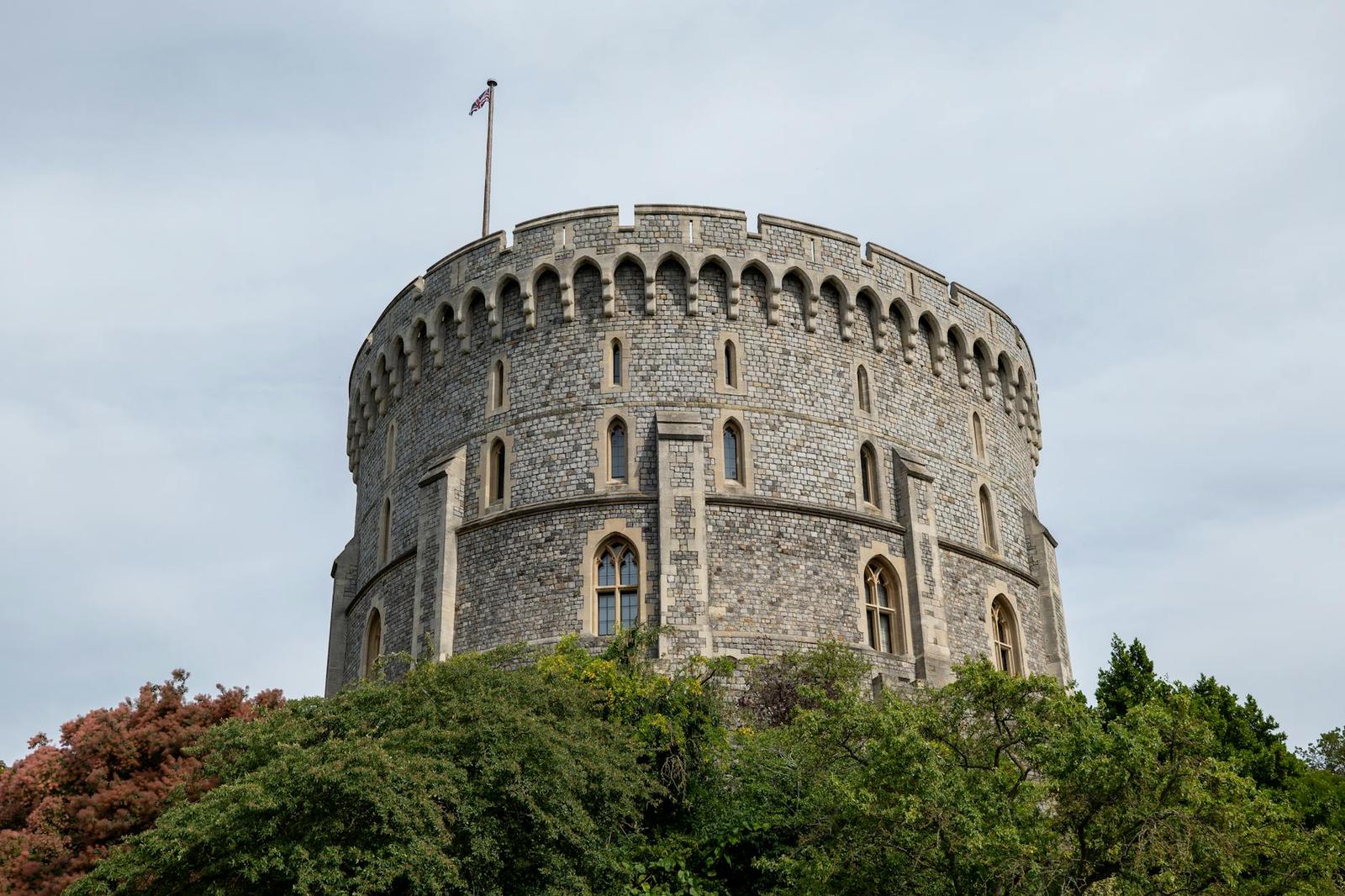 Historic tower of Windsor Castle surrounded by lush greenery, England