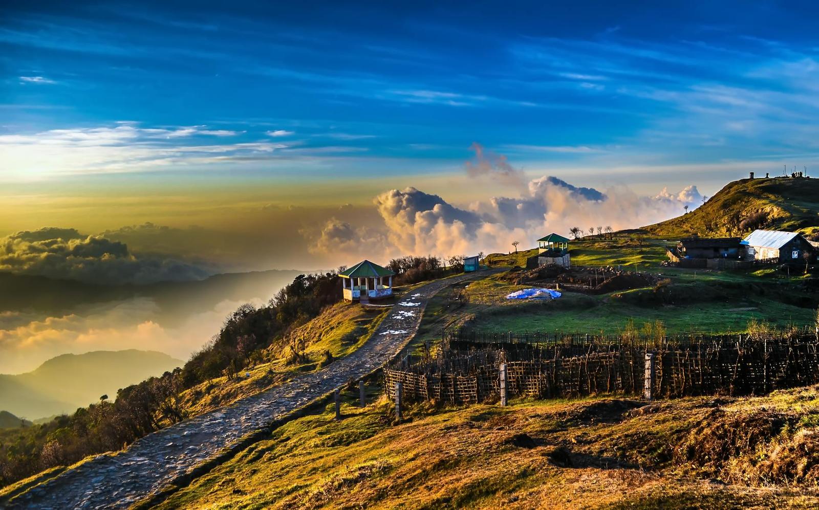 A ridge-top village bordered by a stone path above cloud-filled valleys