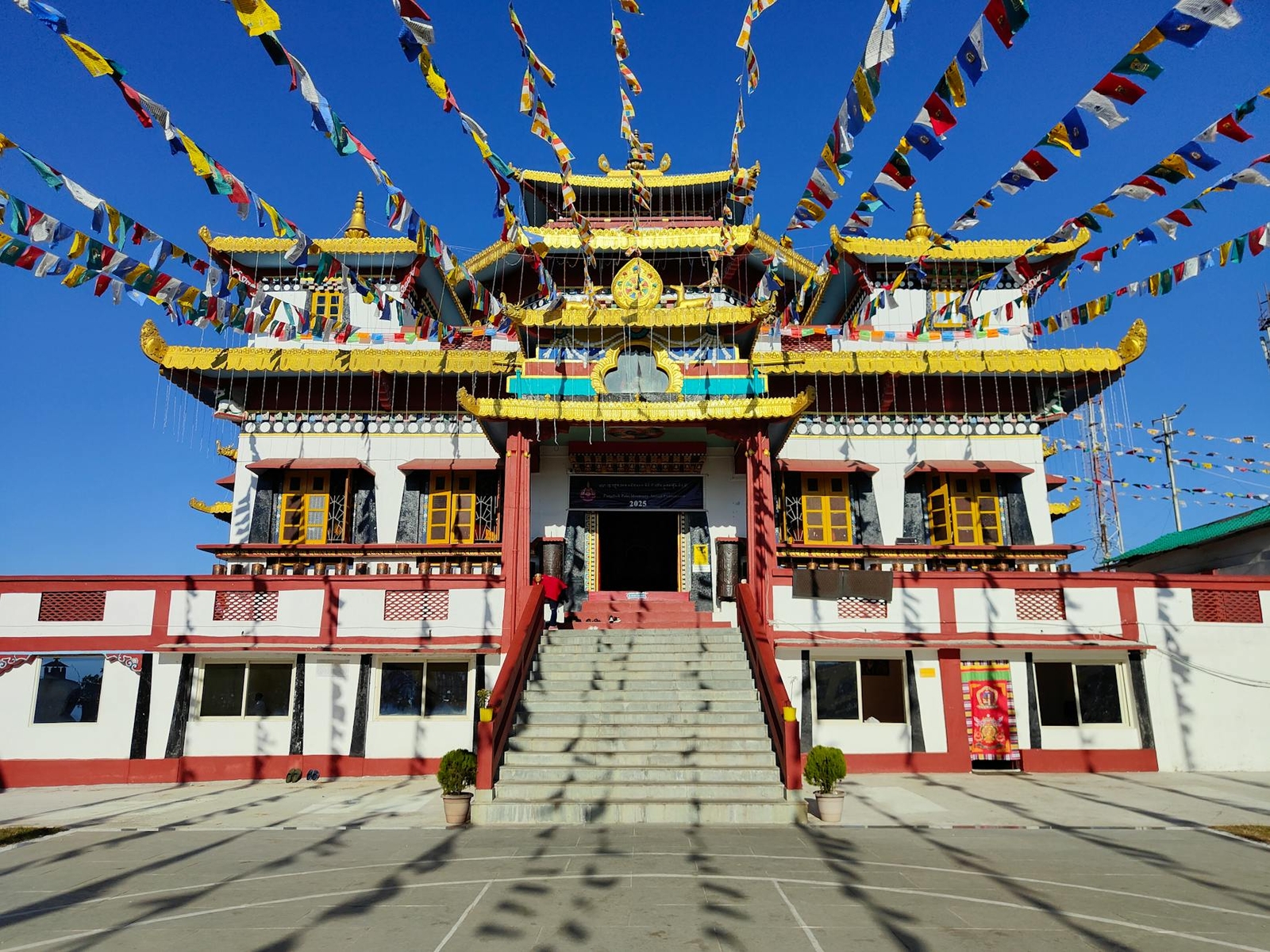 A monastery entrance strung with prayer flags above a wide stone stairway