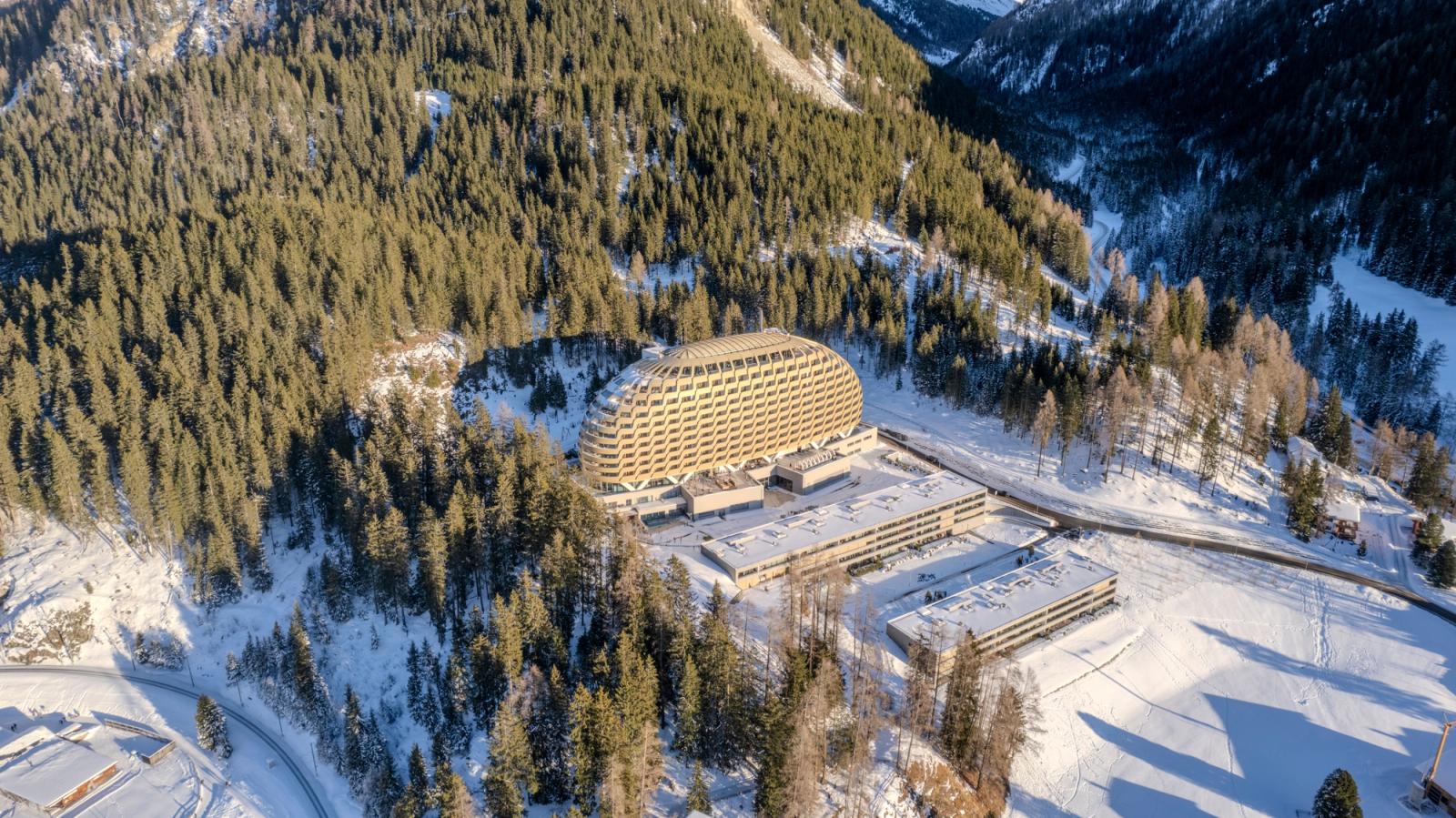 Stunning aerial view of a modern hotel surrounded by snowy forests in the Swiss Alps, Davos