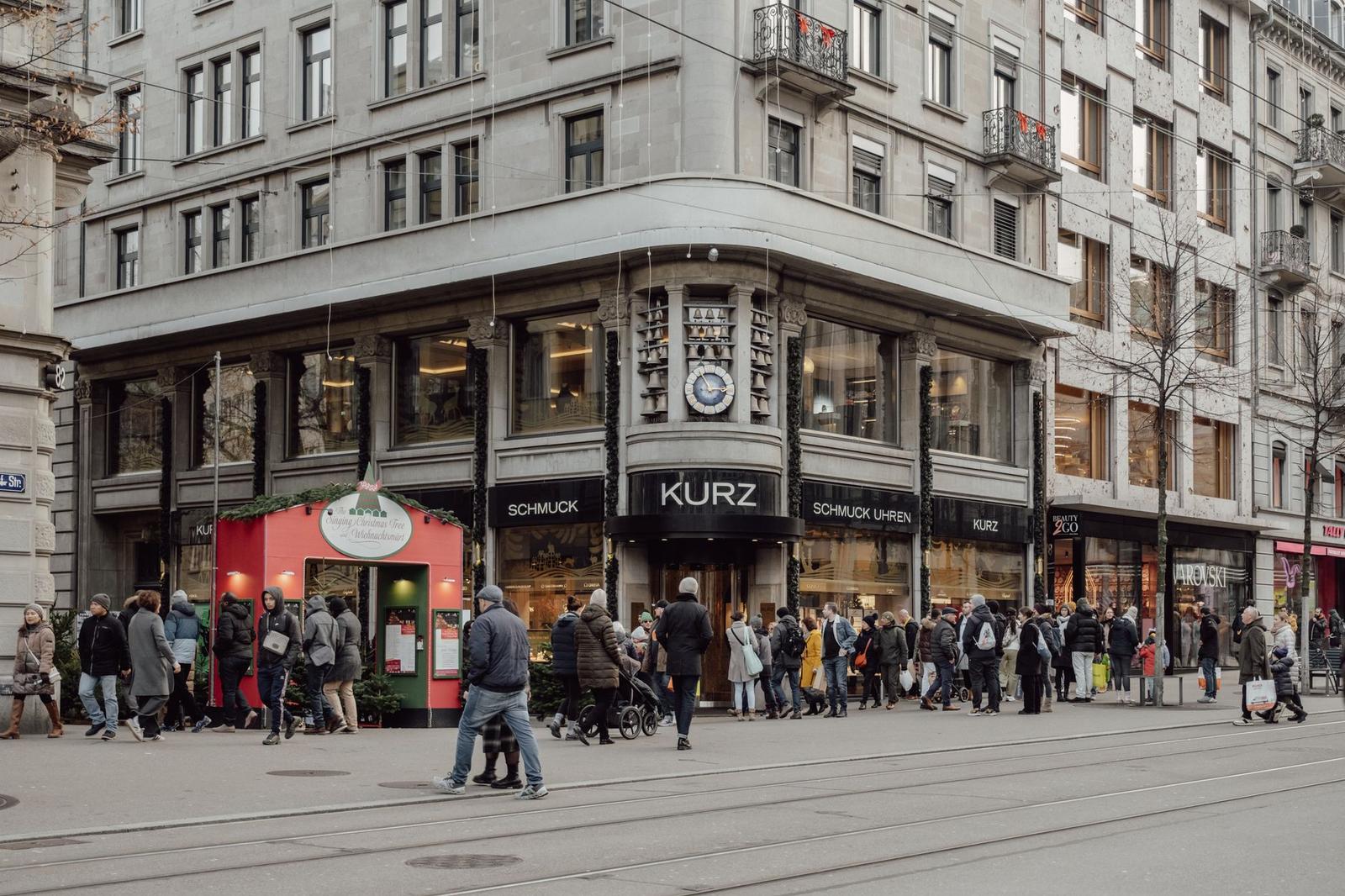 Shoppers crowding a corner storefront on a busy city street