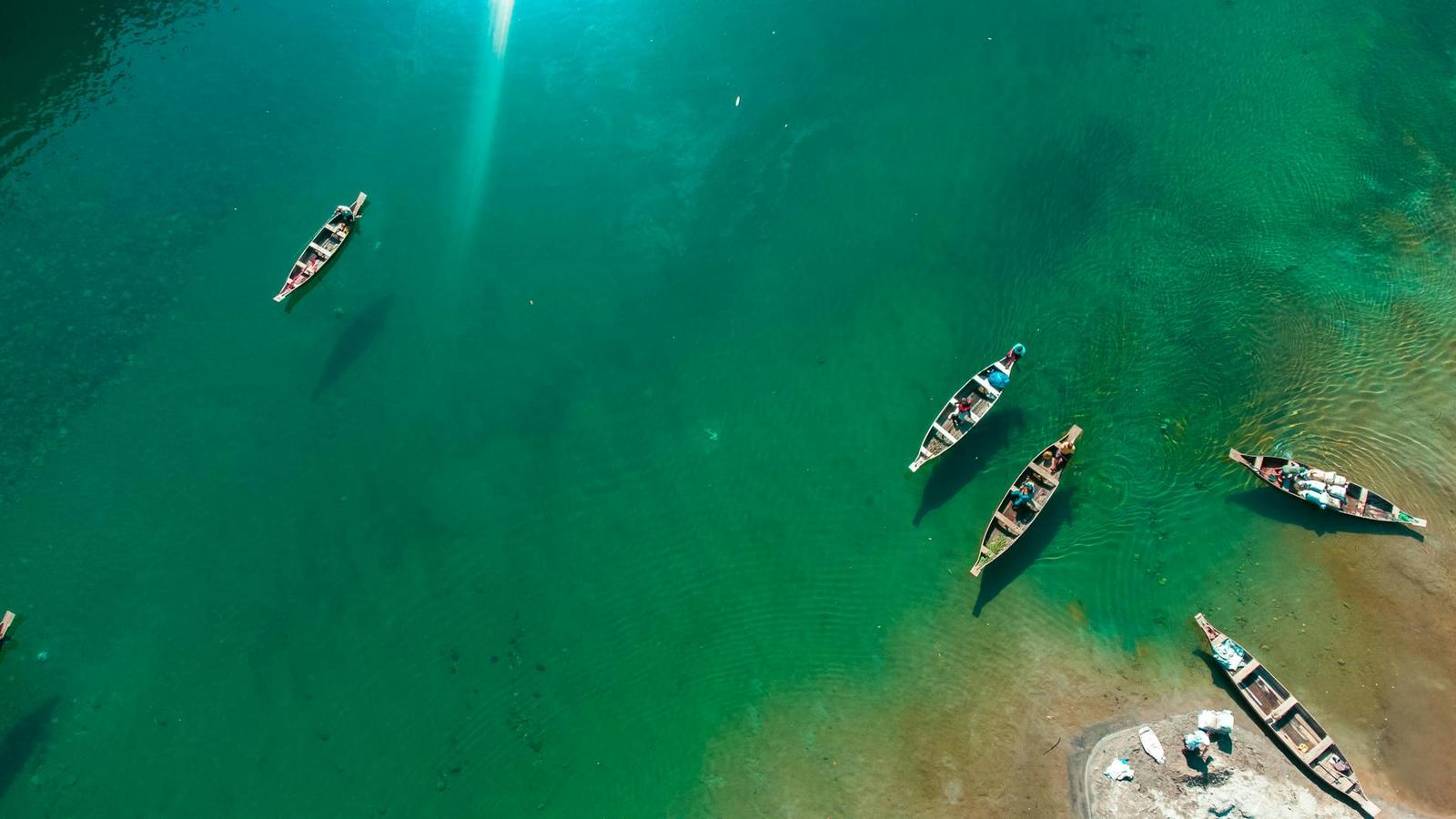 Aerial view of narrow wooden boats scattered across turquoise water