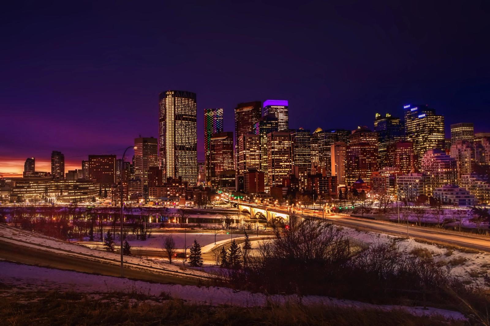 Stunning view of the illuminated Calgary skyline featuring skyscrapers and vibrant city lights at dusk