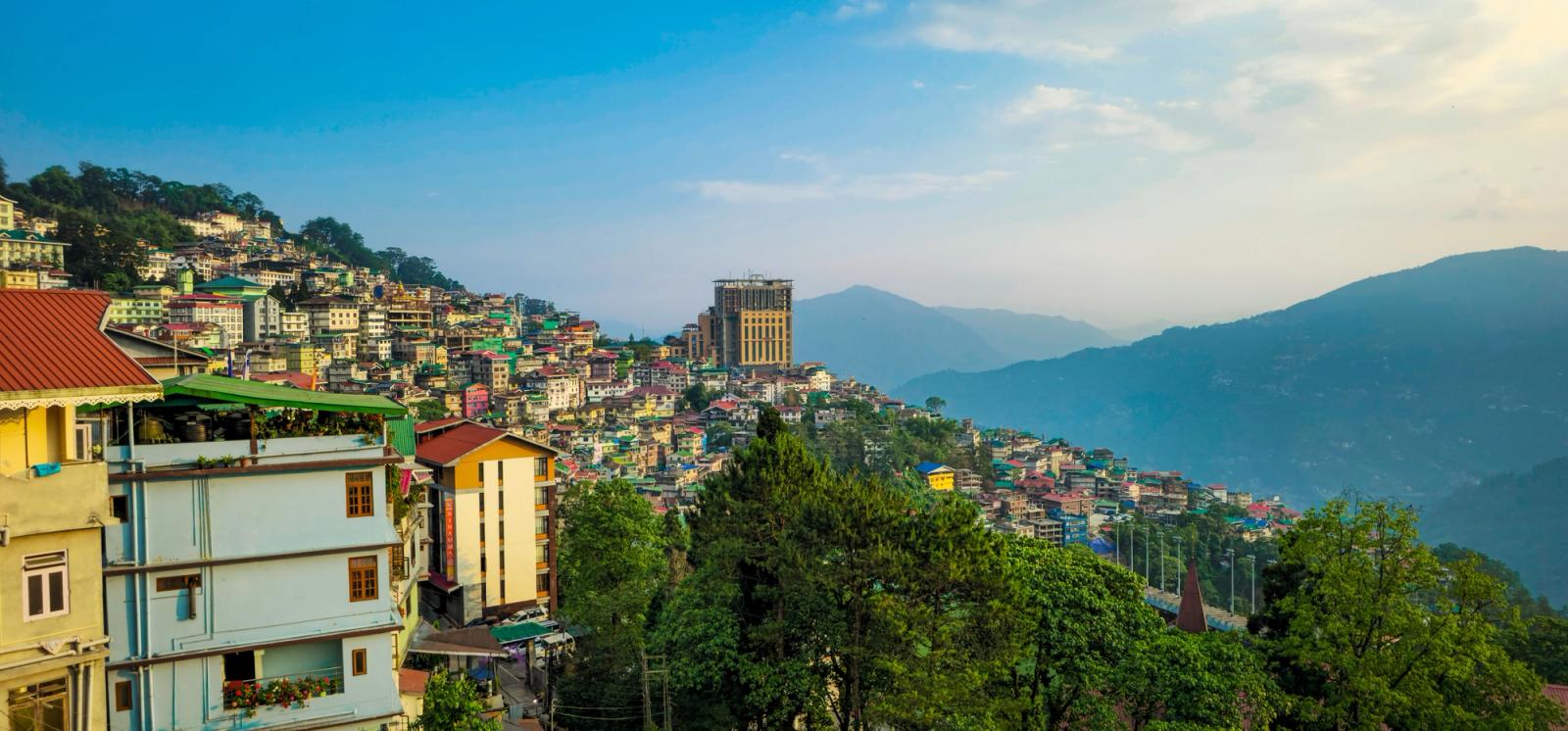 Colourful hillside town buildings stacked against forested mountains