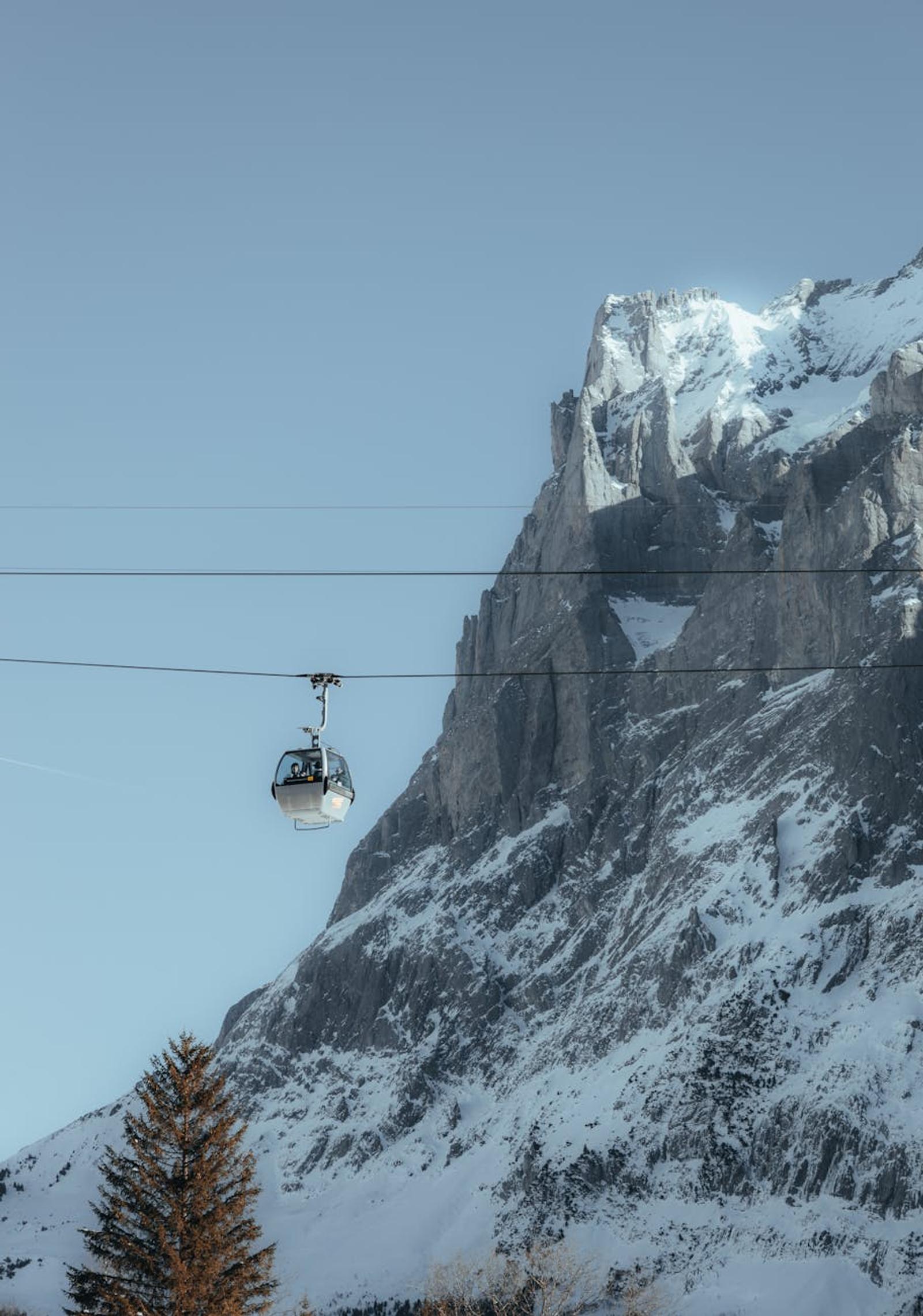 Suspended cable car glides by majestic snowy mountain