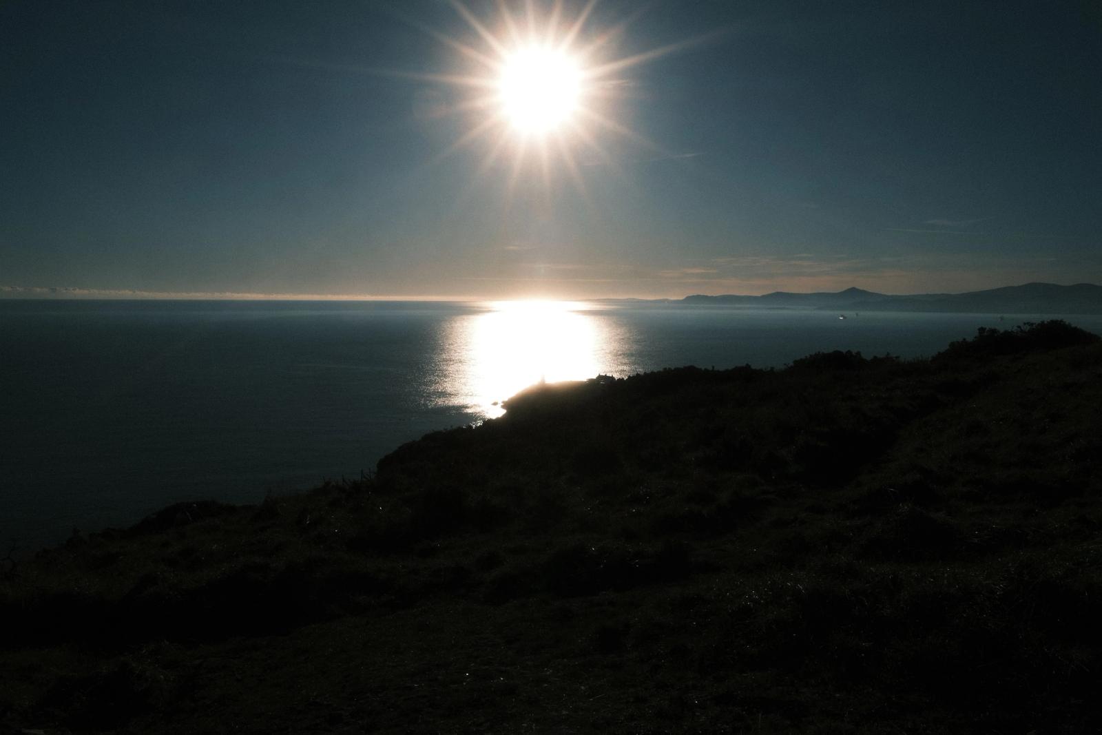 A breathtaking sunset view over Dublin's coastal landscape, showcasing the sun's reflection on the ocean