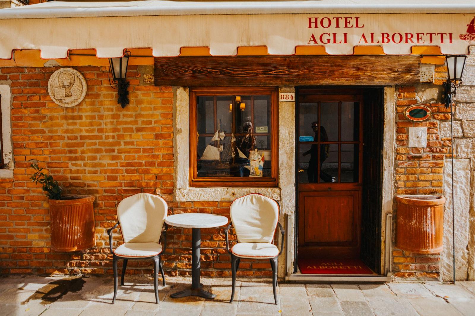 Small brick hotel entrance with a bistro table and two chairs outside