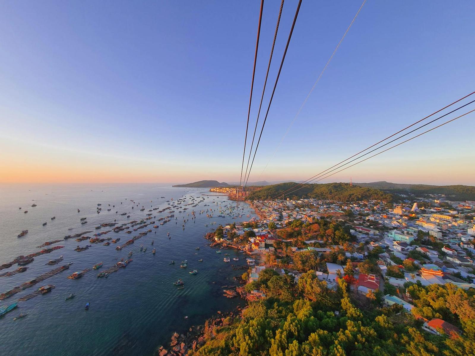 Aerial view from a cable car descending toward a harbour town at sunset