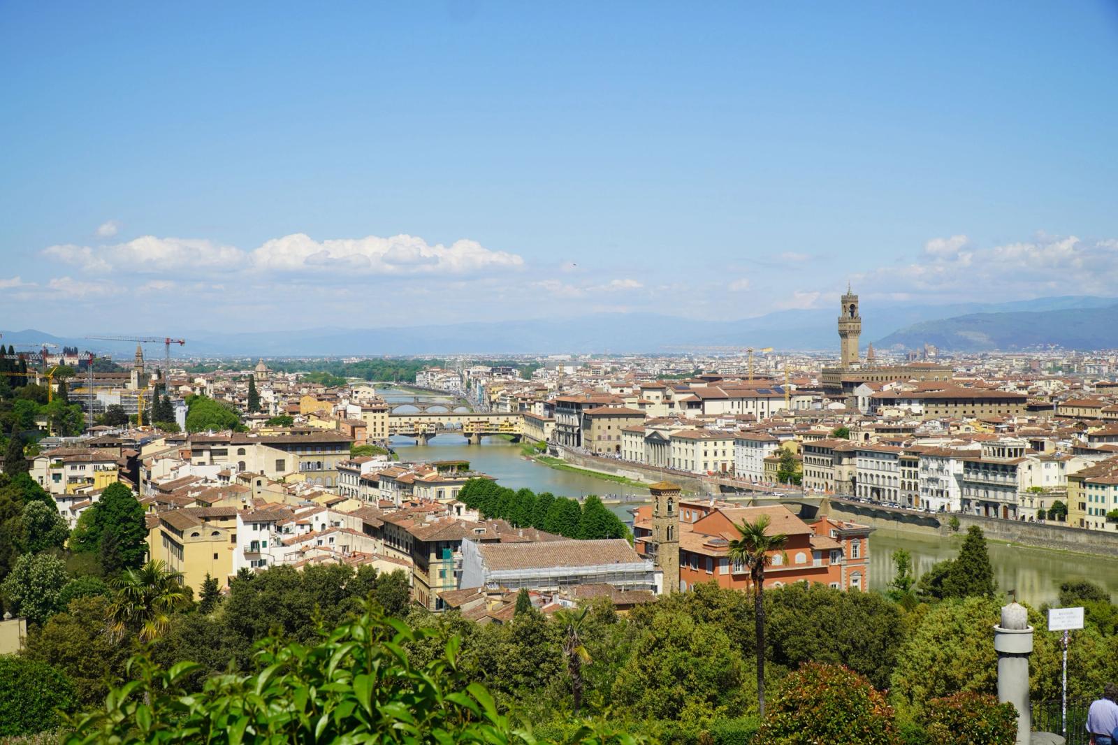 View over a river city from a hillside terrace with a bell tower in the distance