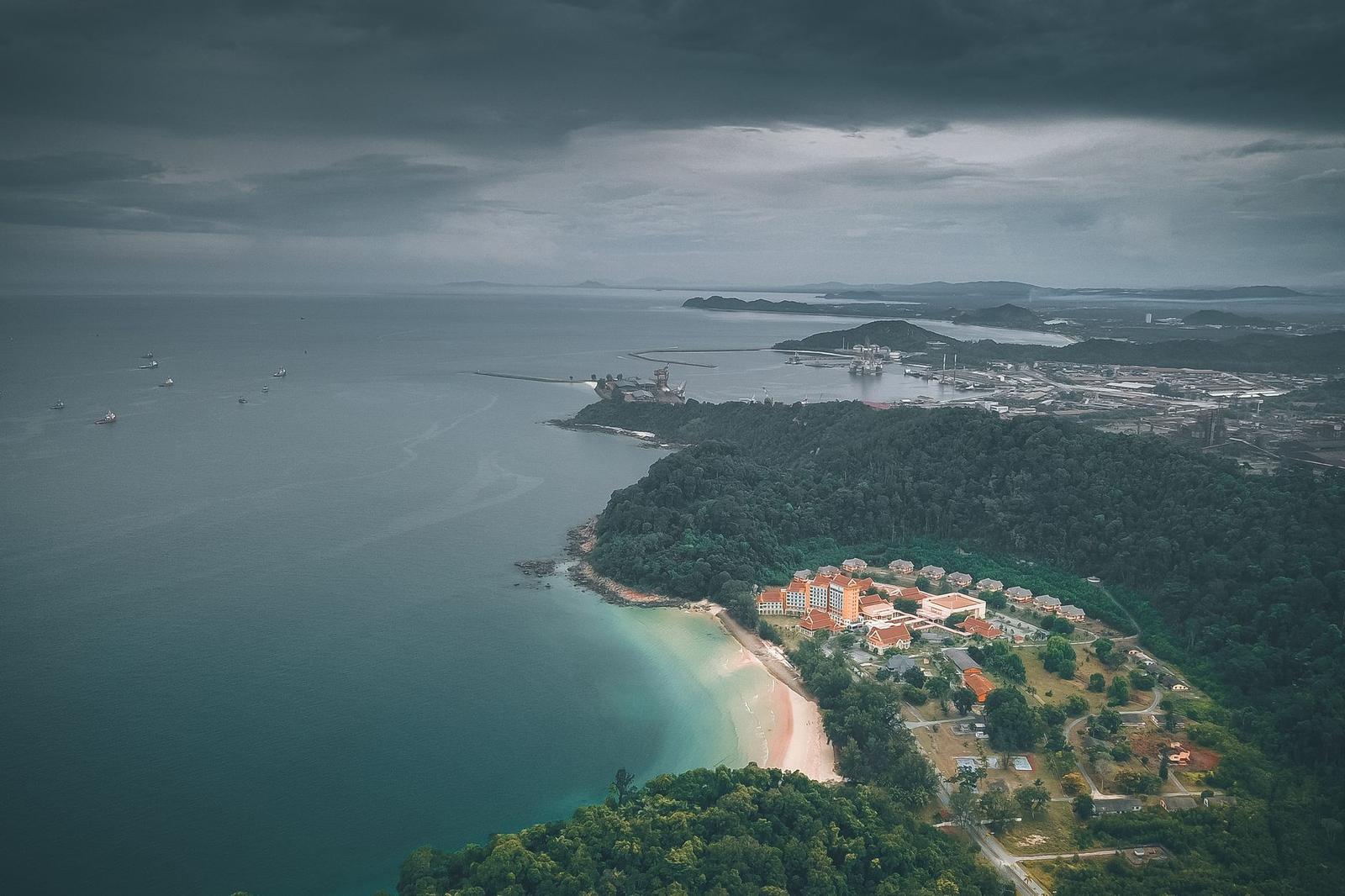 Aerial view of a resort bay on a forested coastline under storm clouds