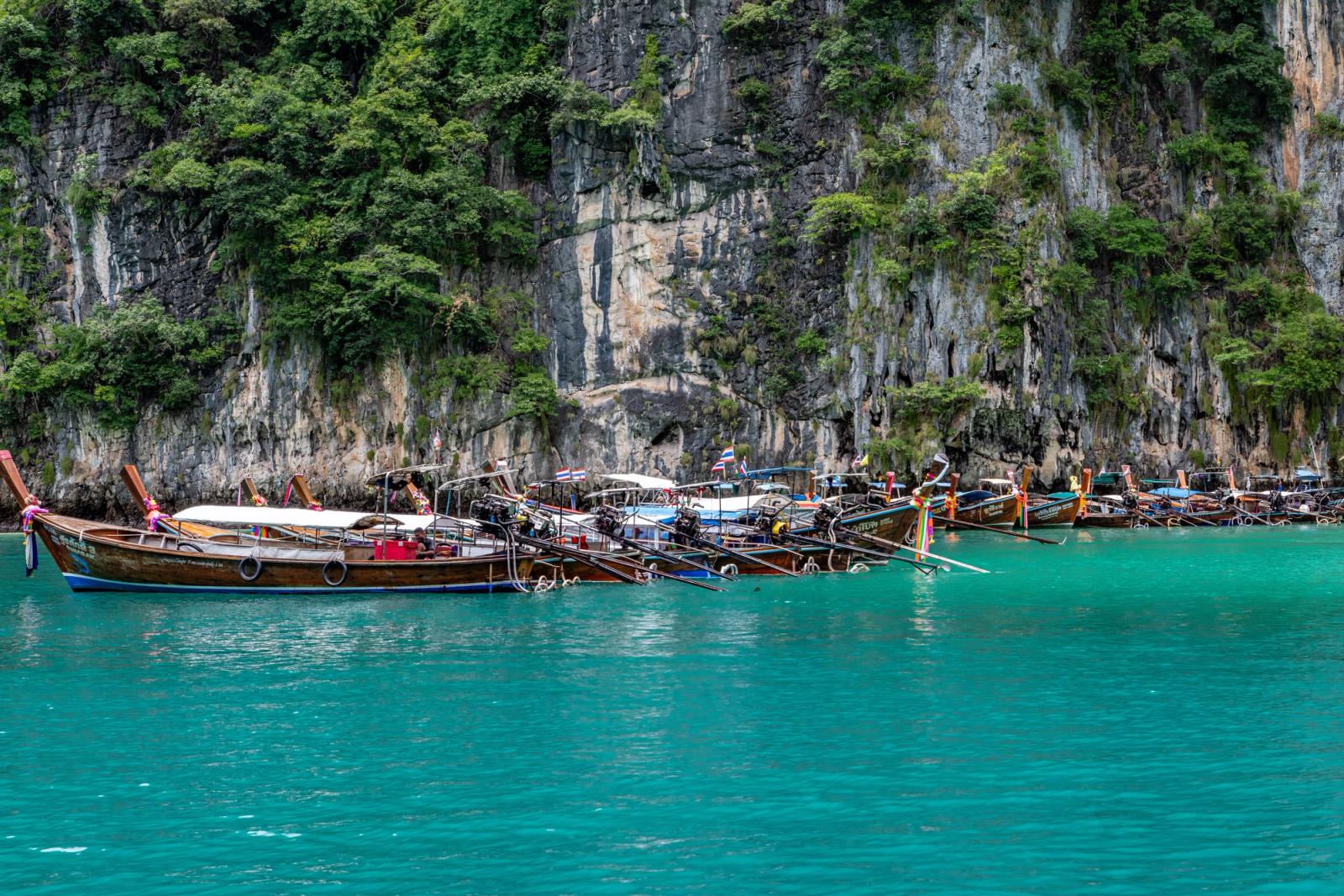 Scenic view of traditional longtail boats moored against cliffs in Phuket, Thailand's turquoise waters