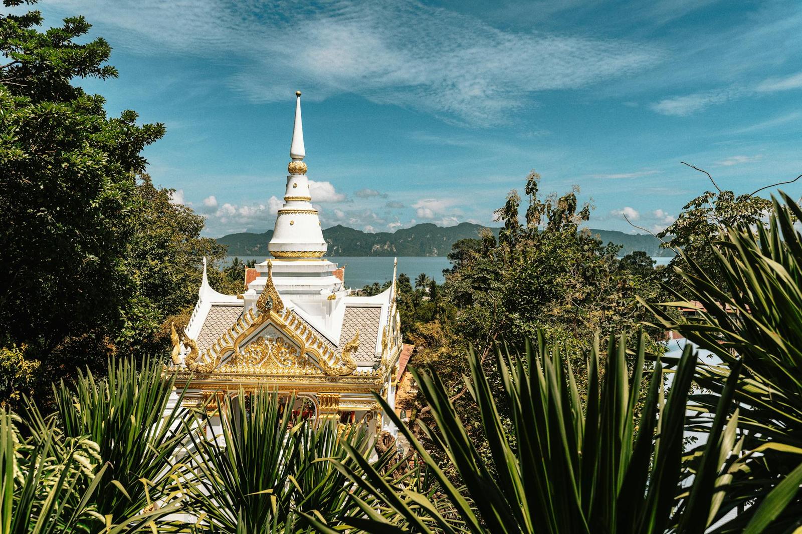 White temple spire framed by palm fronds overlooking a coastal bay