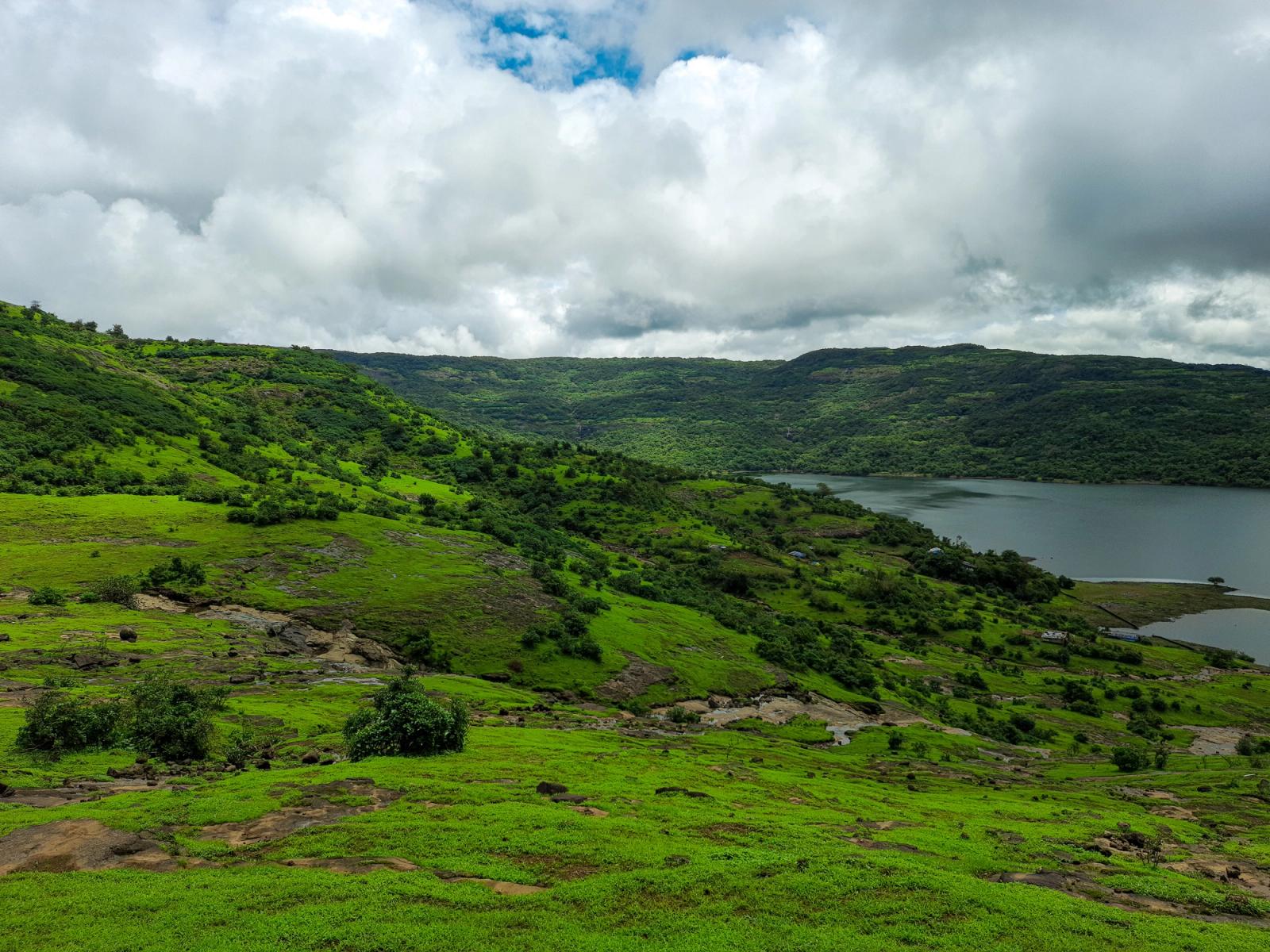 Scenic view of green hills and lake under cloudy skies in Lonavla, MH, India