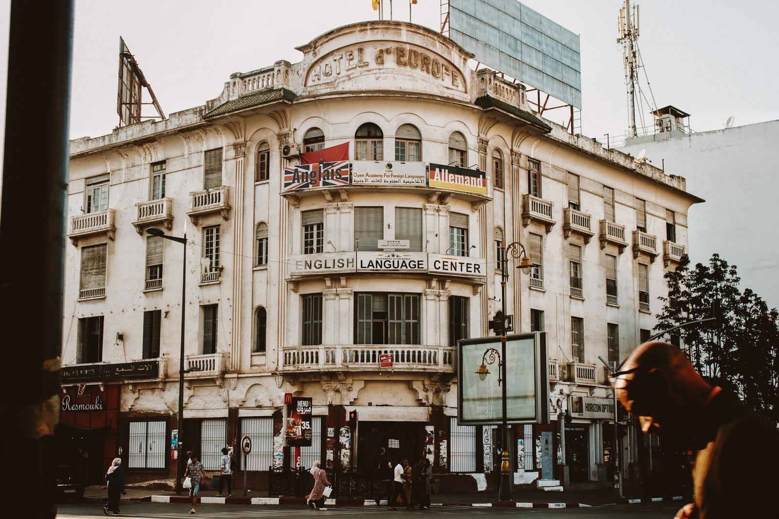 An ornate corner hotel building with balconies above a busy street