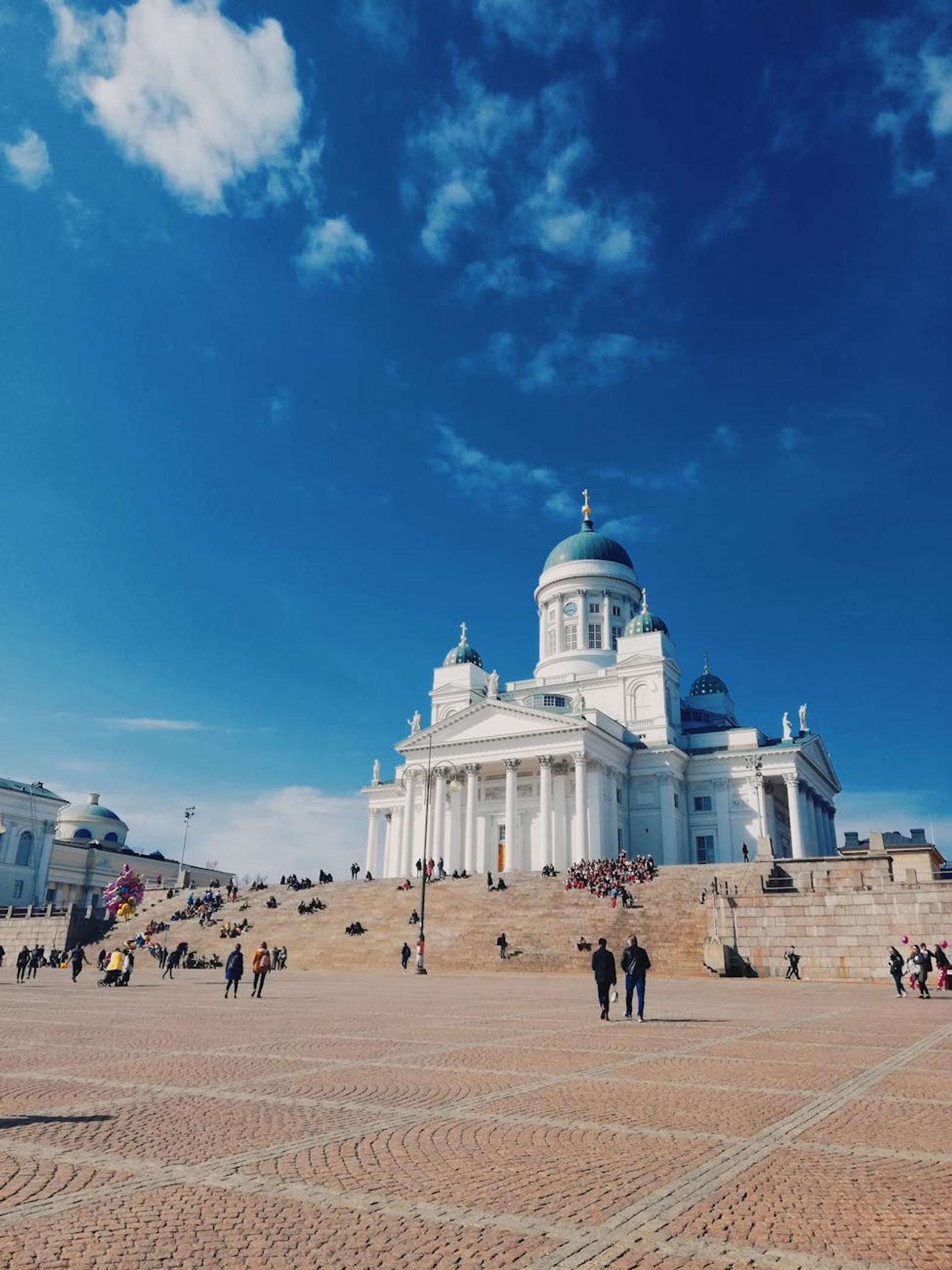 A stunning view of Helsinki Cathedral with people walking on a sunny day under a vibrant blue sky