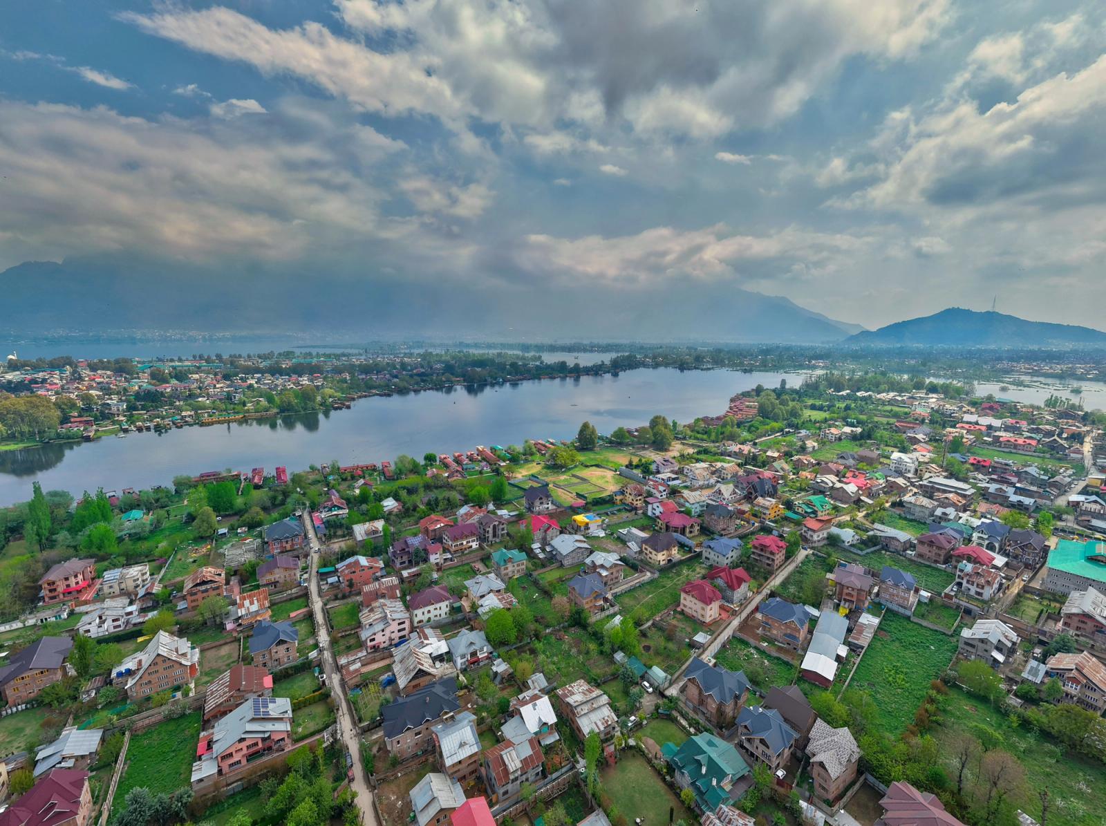 Aerial view of a lakeside town with houses set among green plots and a wide river