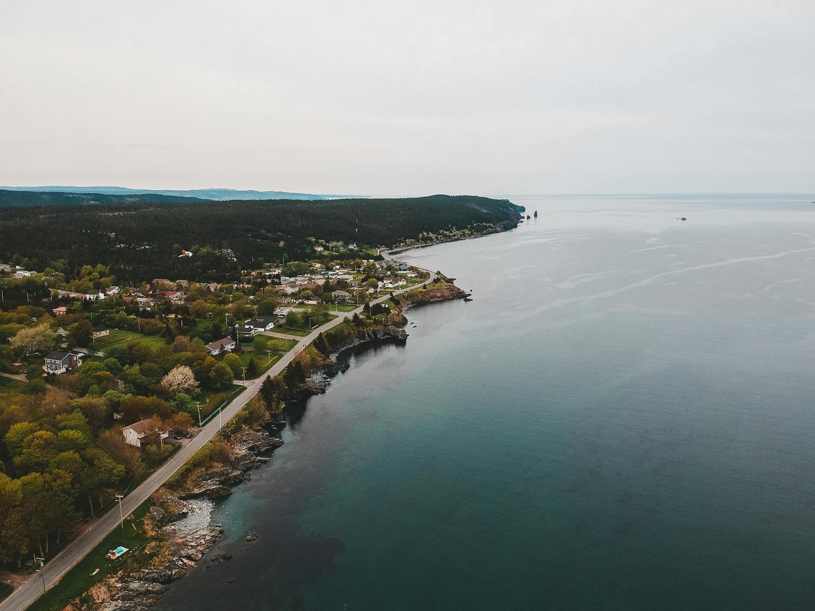 Aerial view of a coastal town along cliffs meeting a calm sea