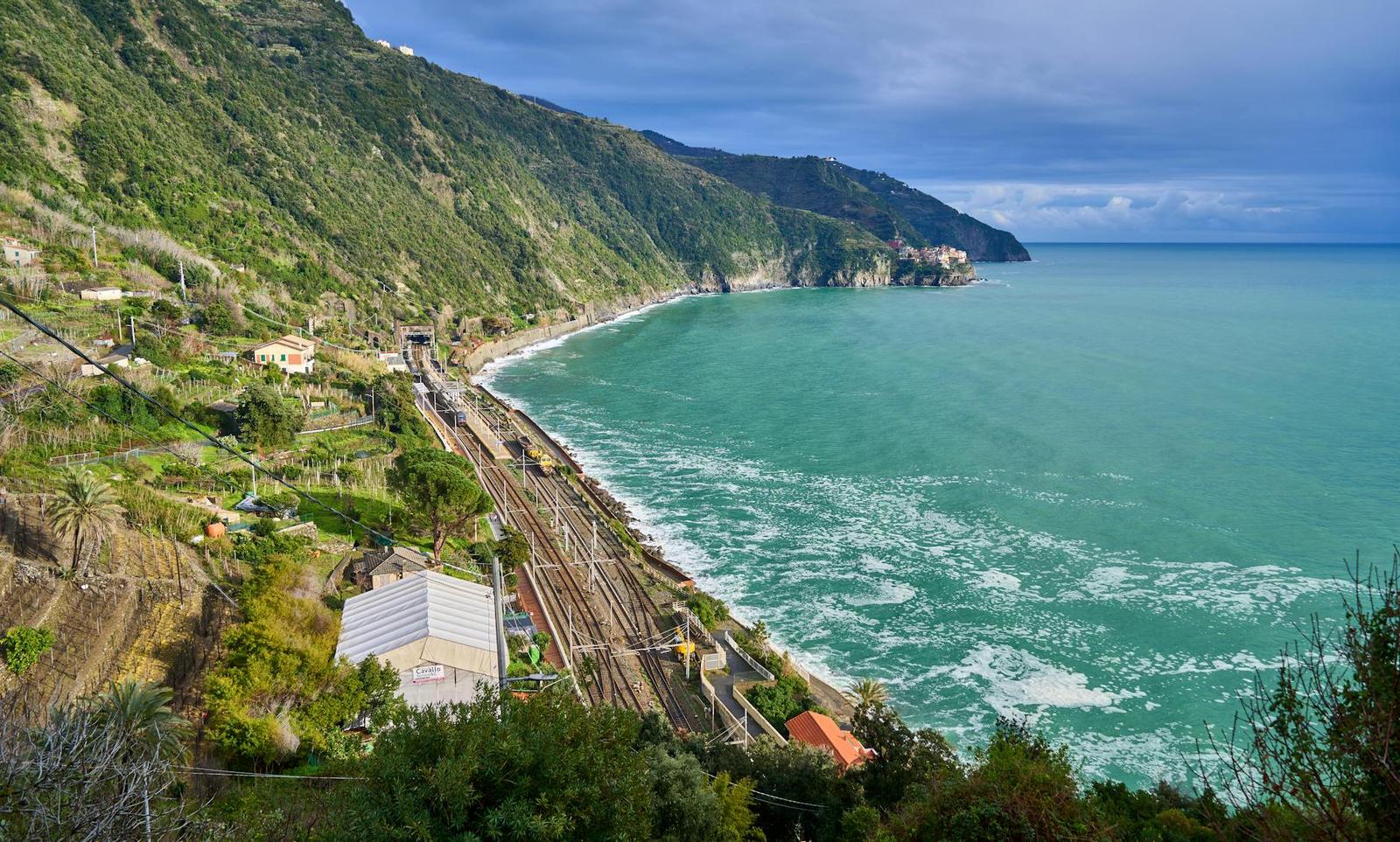 A coastal railway curving along cliffs above a turquoise sea