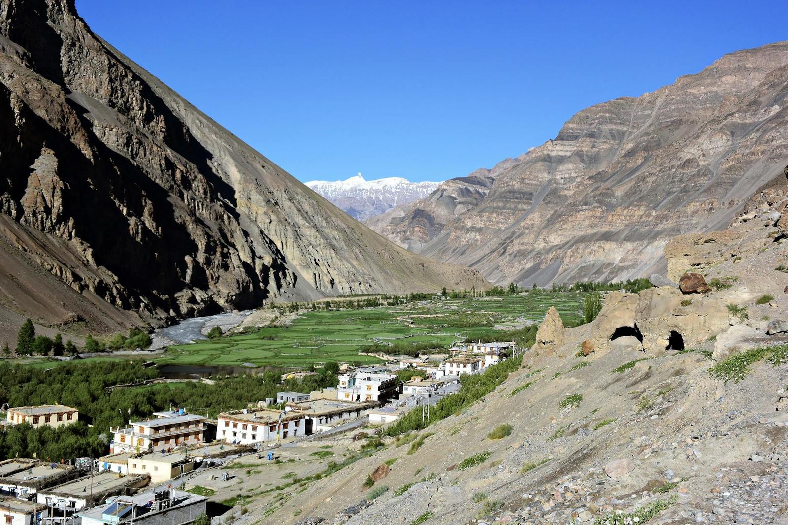 A green farming village in a valley flanked by steep barren mountains